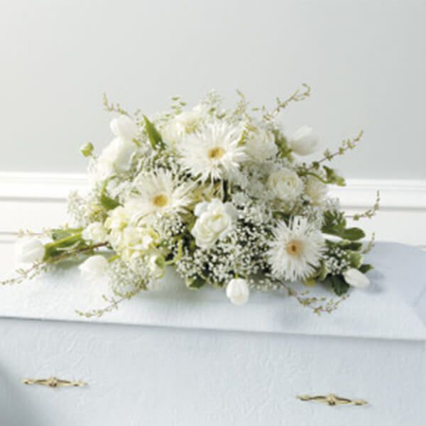 White floral arrangement on a casket with daisies and roses