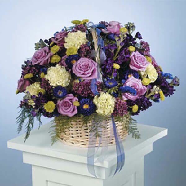 Basket arrangement of purple and yellow flowers with pink roses