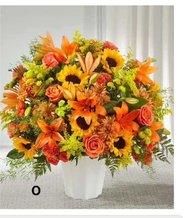 Orange and yellow mixed flower arrangement in a white vase