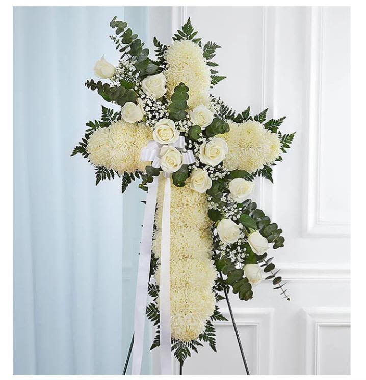 White floral standing cross on an easel with ribbon
