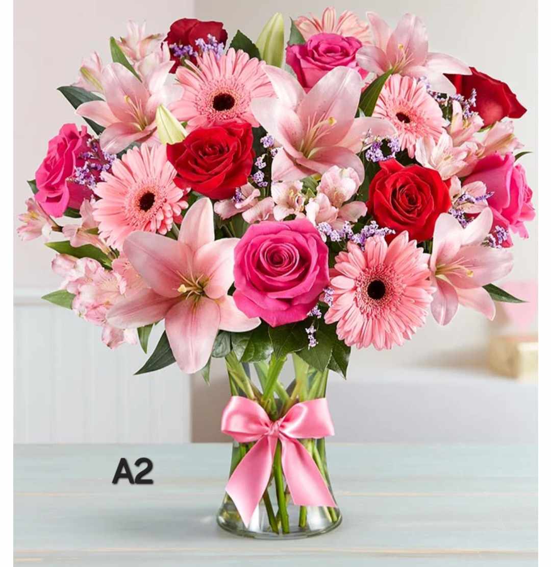 Pink and red mixed bouquet in a clear glass vase with a pink ribbon