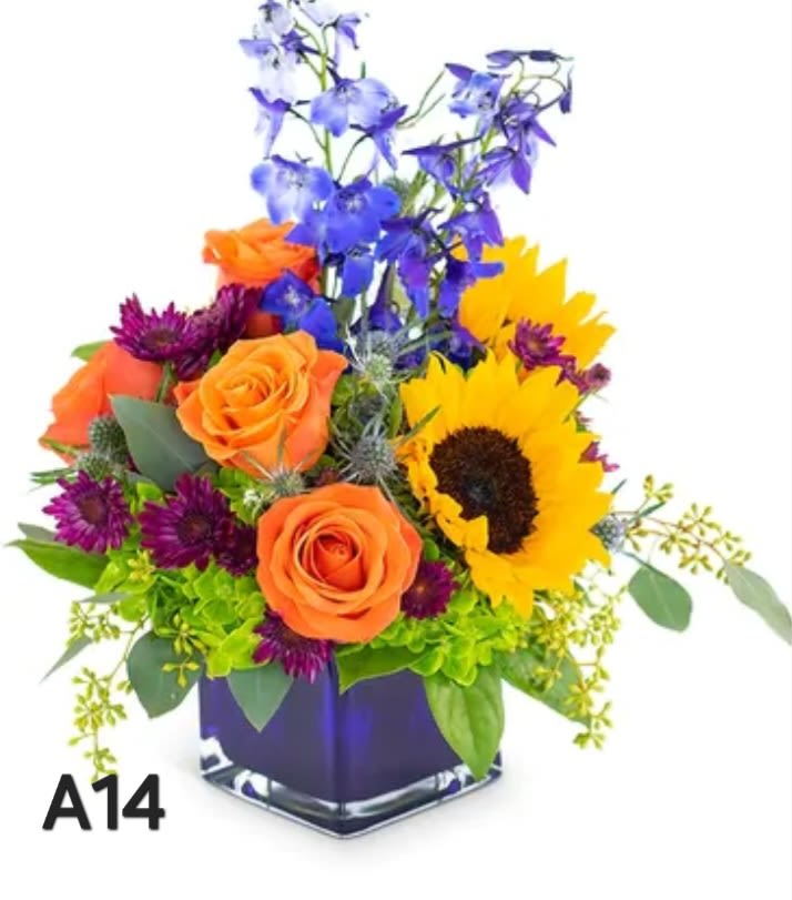 Colorful bouquet with roses, sunflower, and blue flowers in a square vase