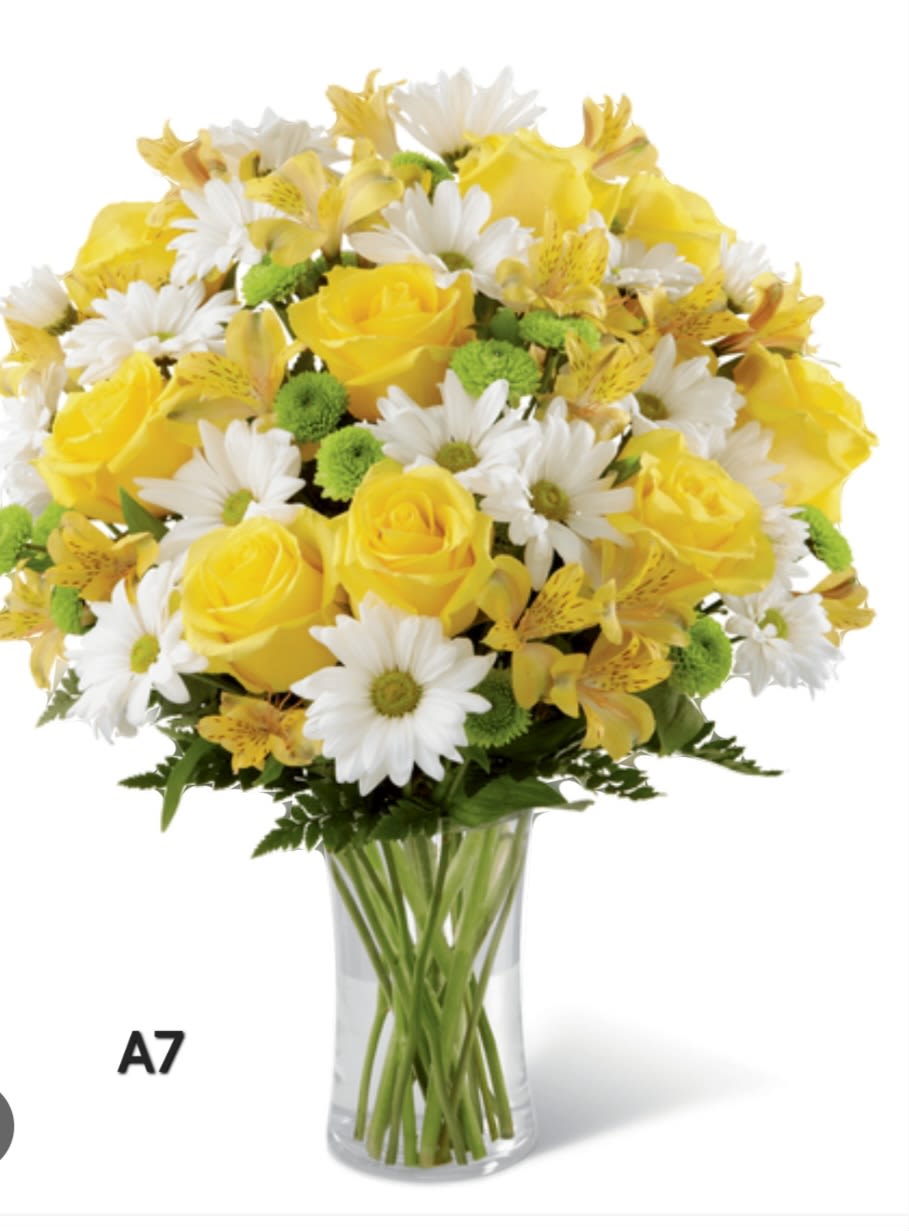 Yellow roses and white daisies arranged in a clear glass vase