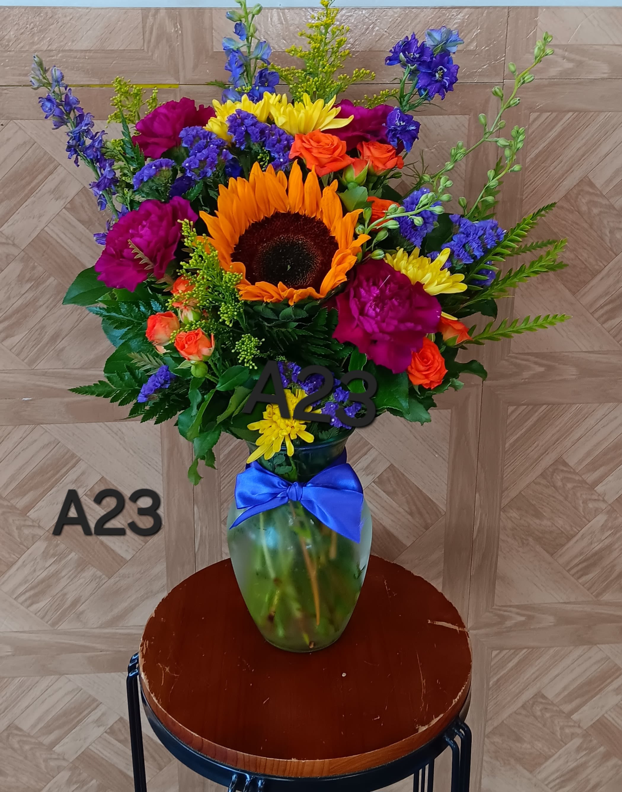 Colorful bouquet with a sunflower in a glass vase tied with a blue ribbon