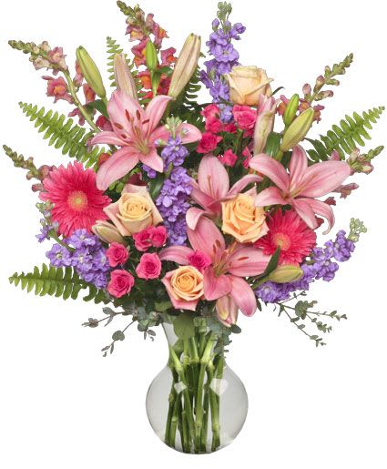 Mixed bouquet of pink lilies, roses, and purple flowers in a glass vase