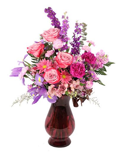 Pink and purple mixed flower arrangement in a red glass vase