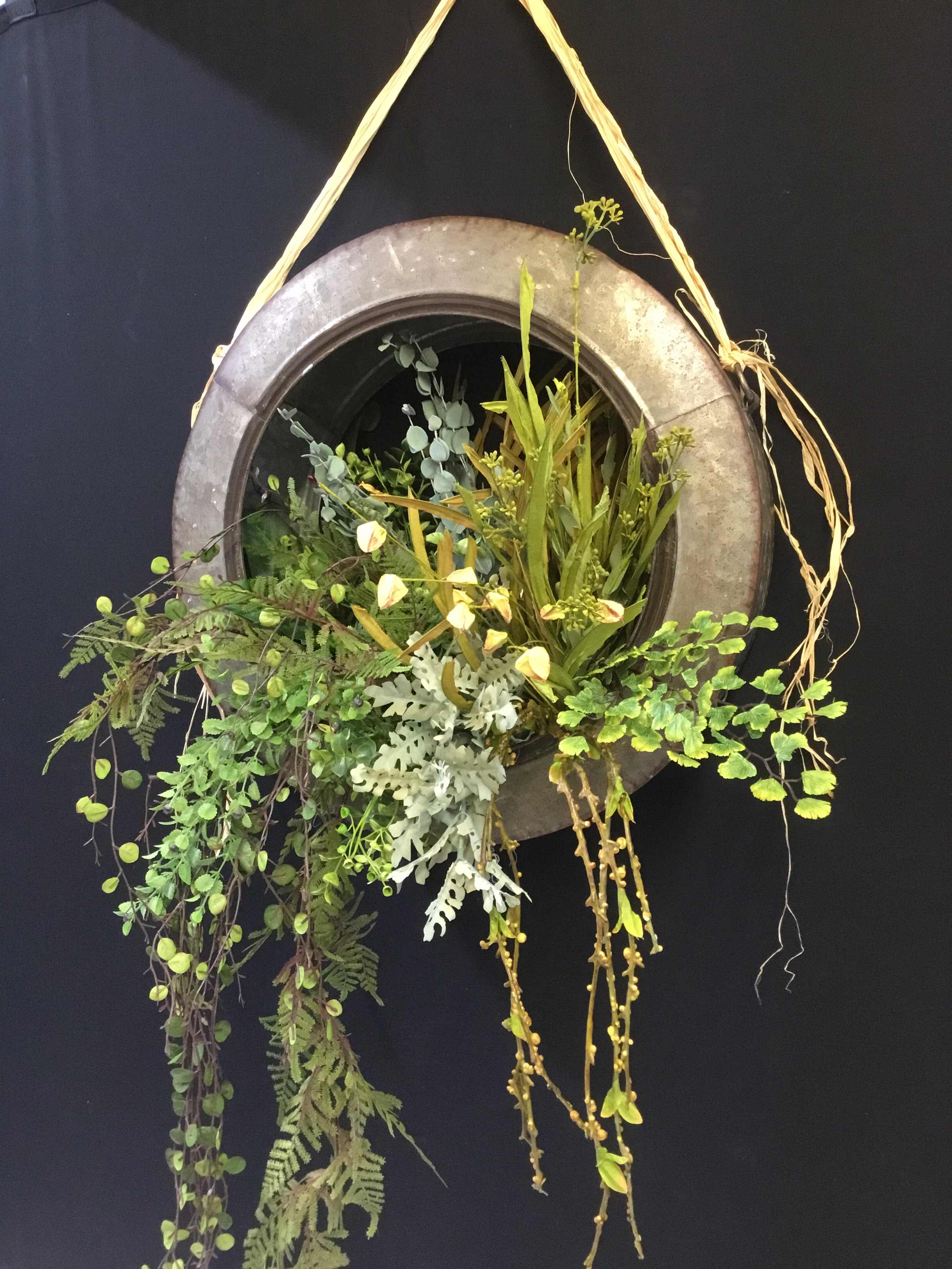 Hanging circular planter with trailing greenery and small pale flowers