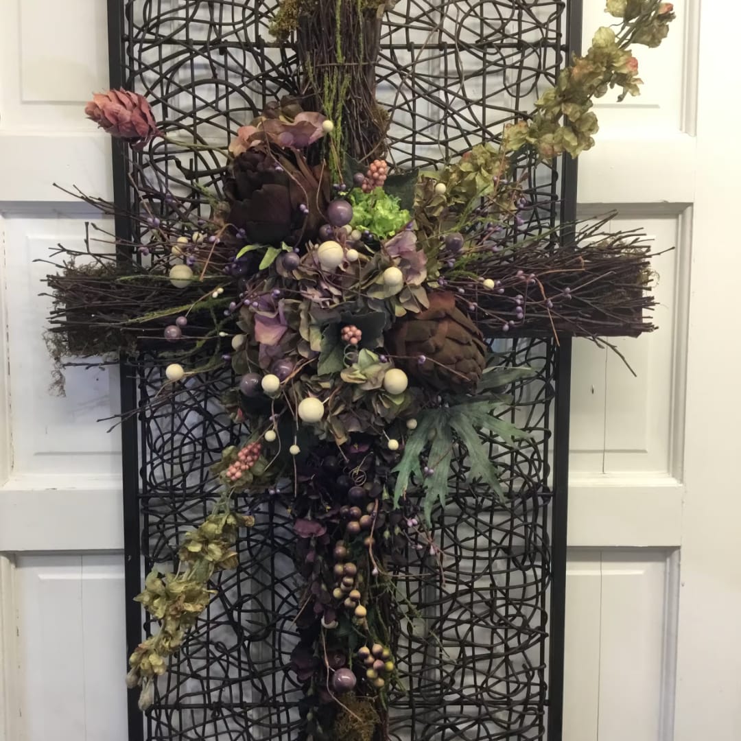 Decorative floral cross with dried flowers and berries on a black lattice frame