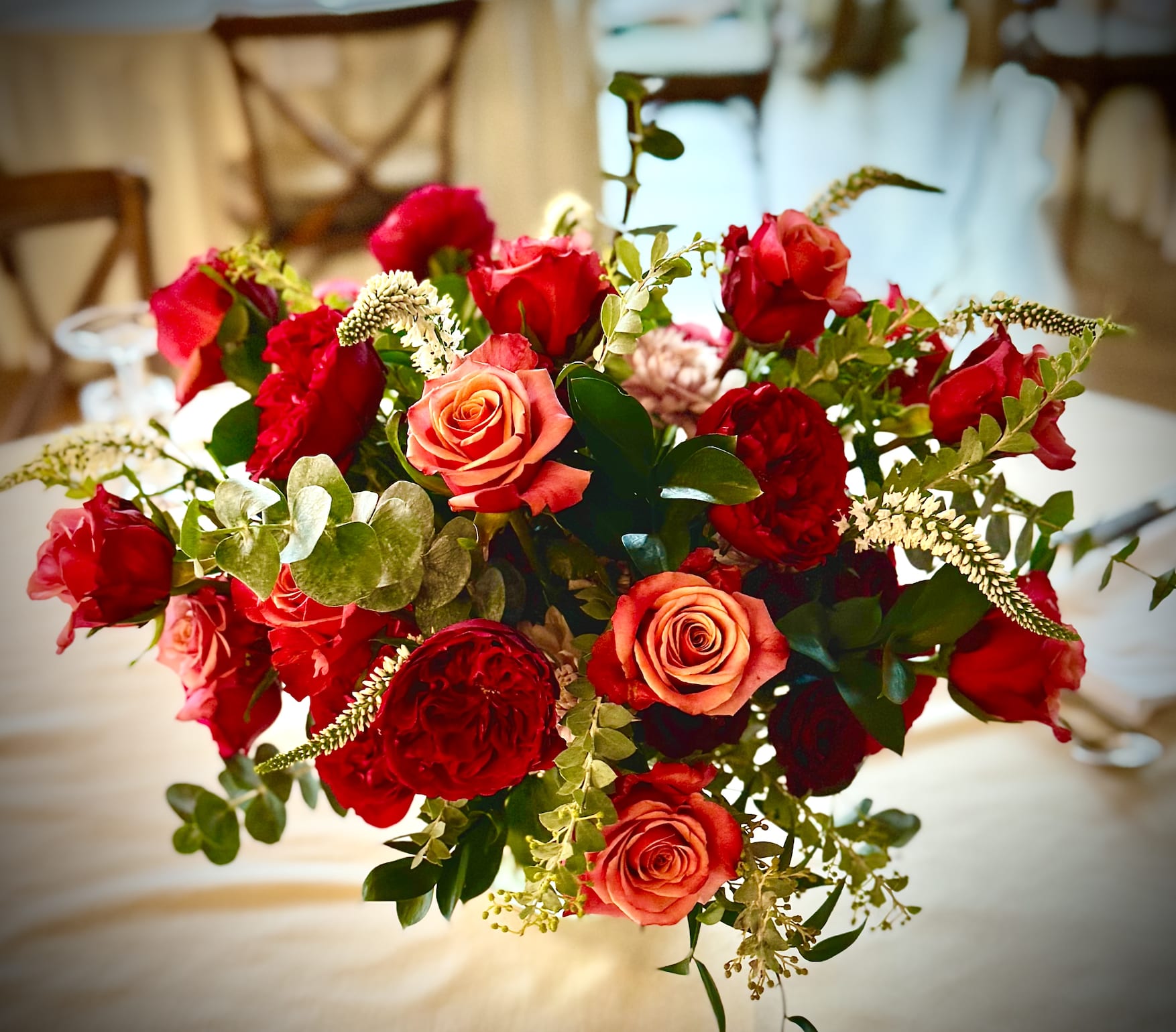 Rounded arrangement of red and orange roses on a table