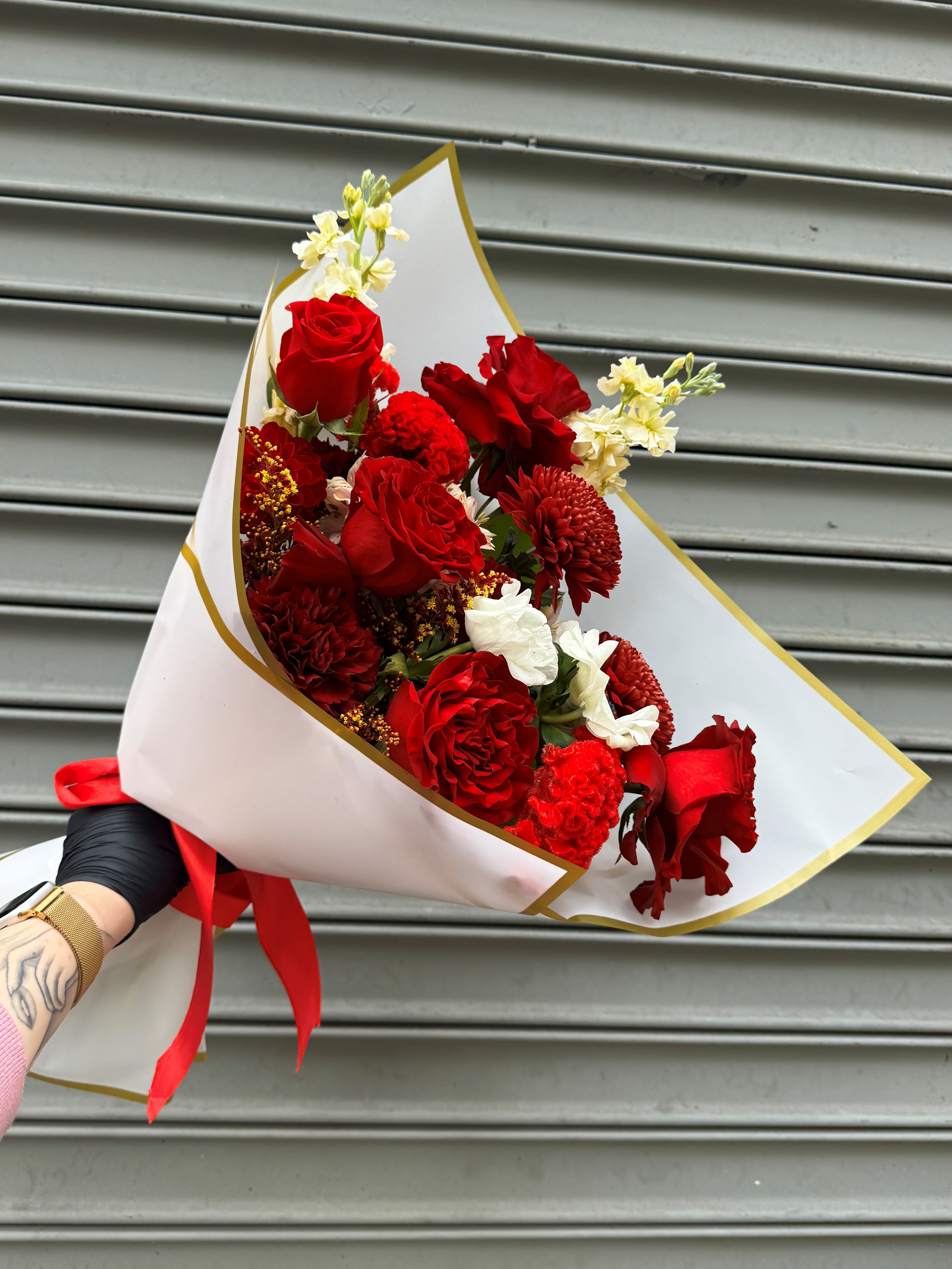 Bouquet of red roses and red carnations wrapped in white paper