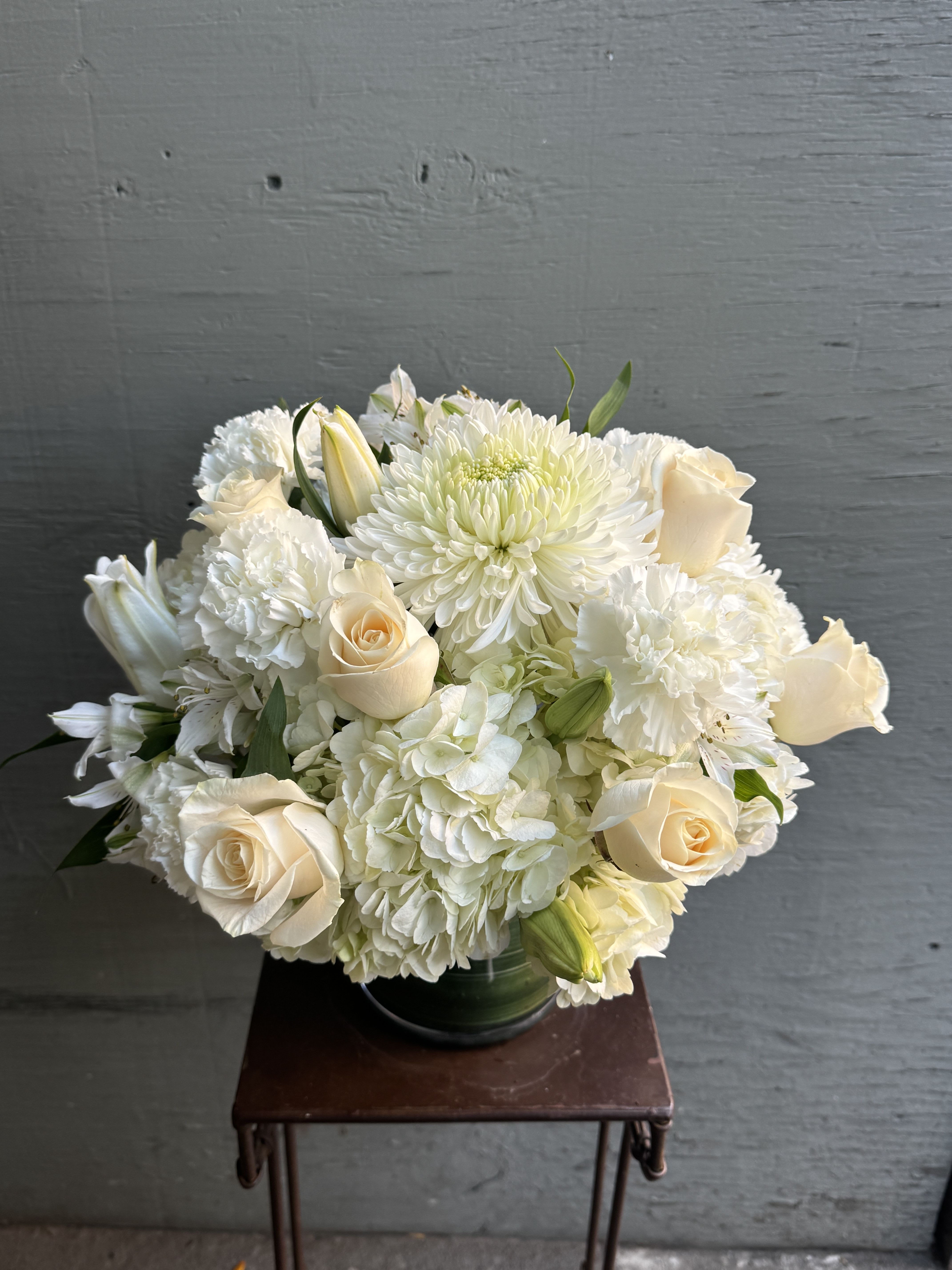White floral bouquet with cream roses and chrysanthemums in a glass vase
