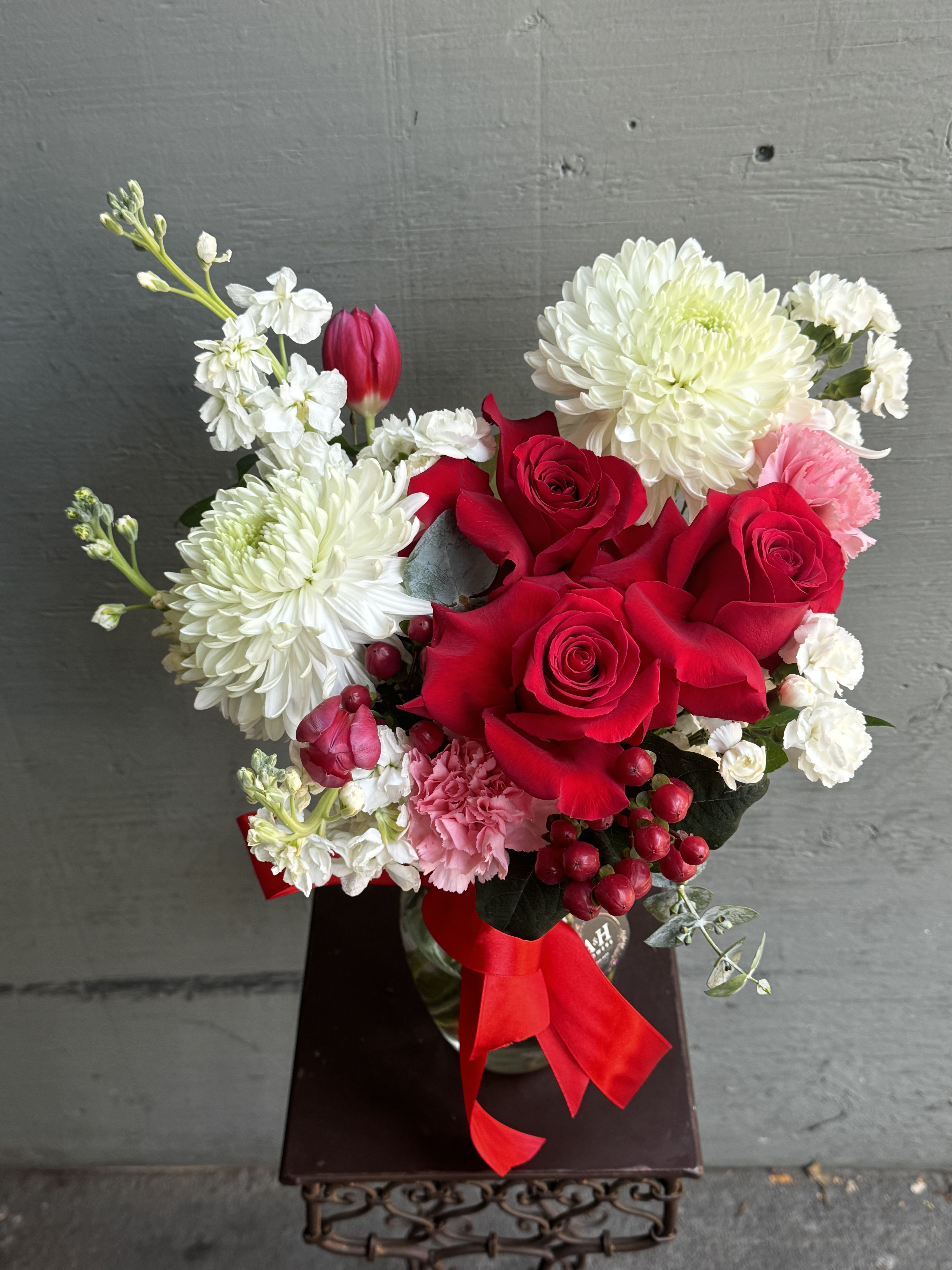 Bouquet of red roses, white chrysanthemums, and pink carnations with a red ribbon