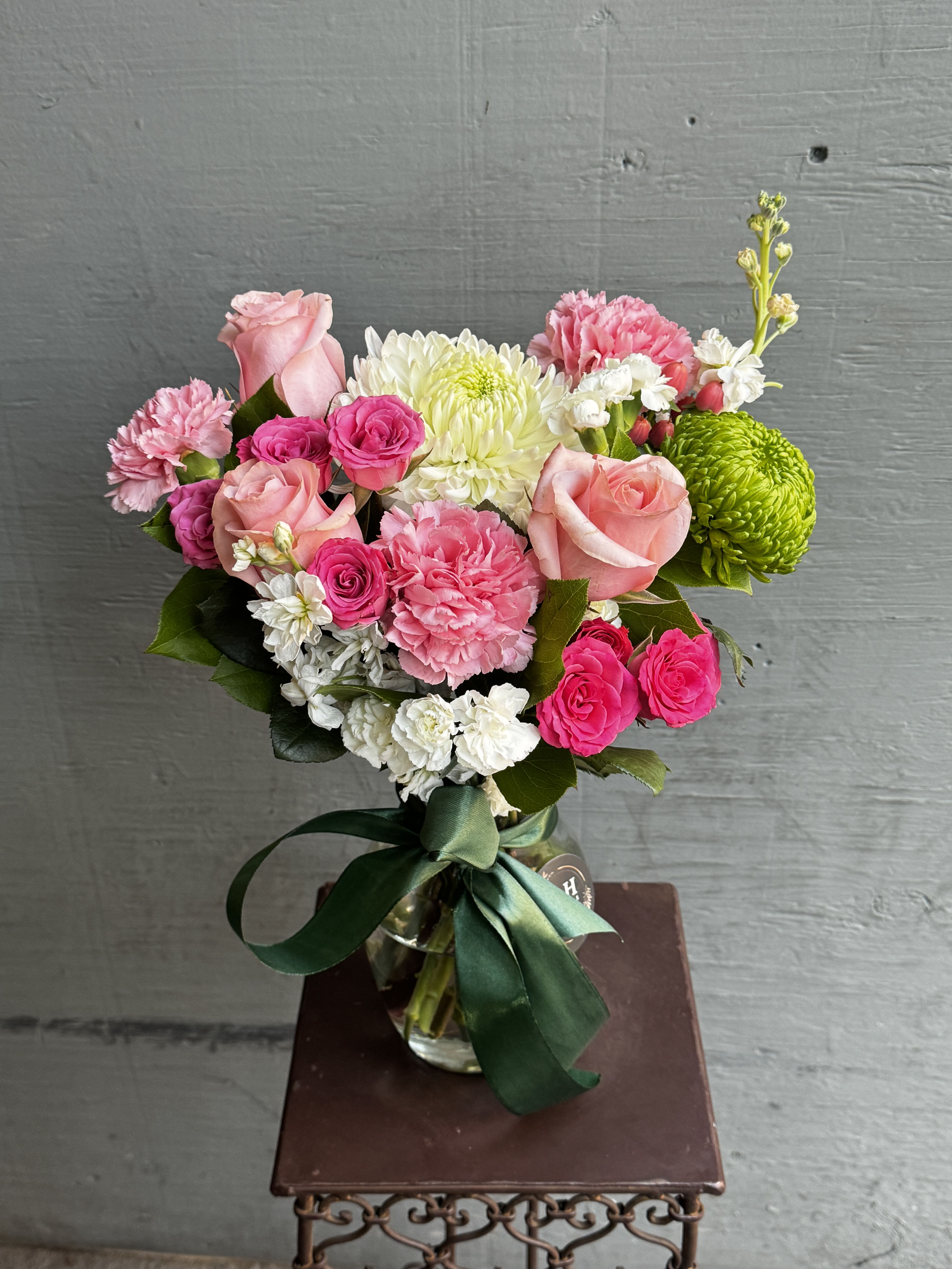 Pink and white mixed bouquet in a glass vase with a green ribbon