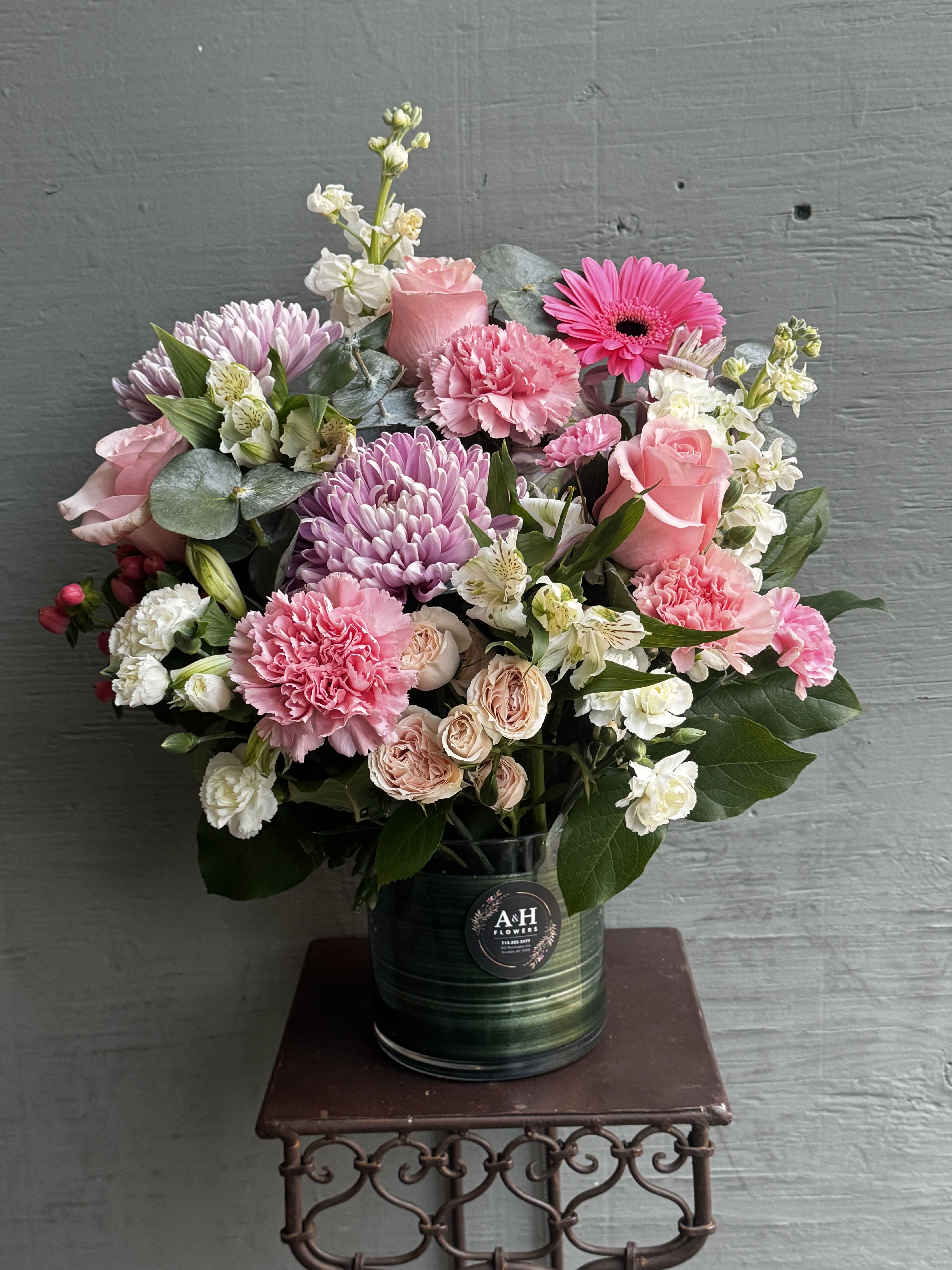 Pink and white mixed flower arrangement in a dark vase