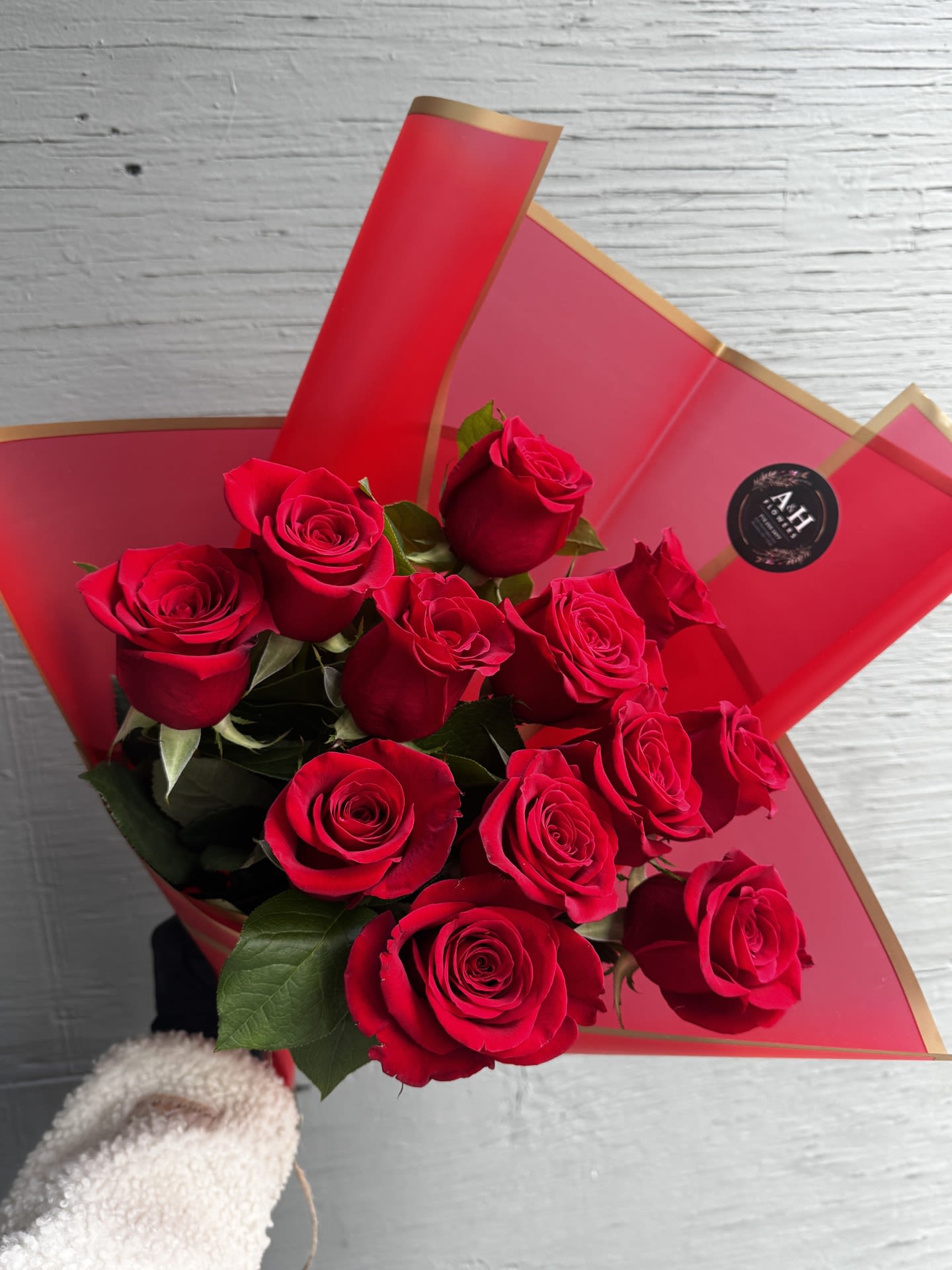 Bouquet of red roses wrapped in red paper with gold trim