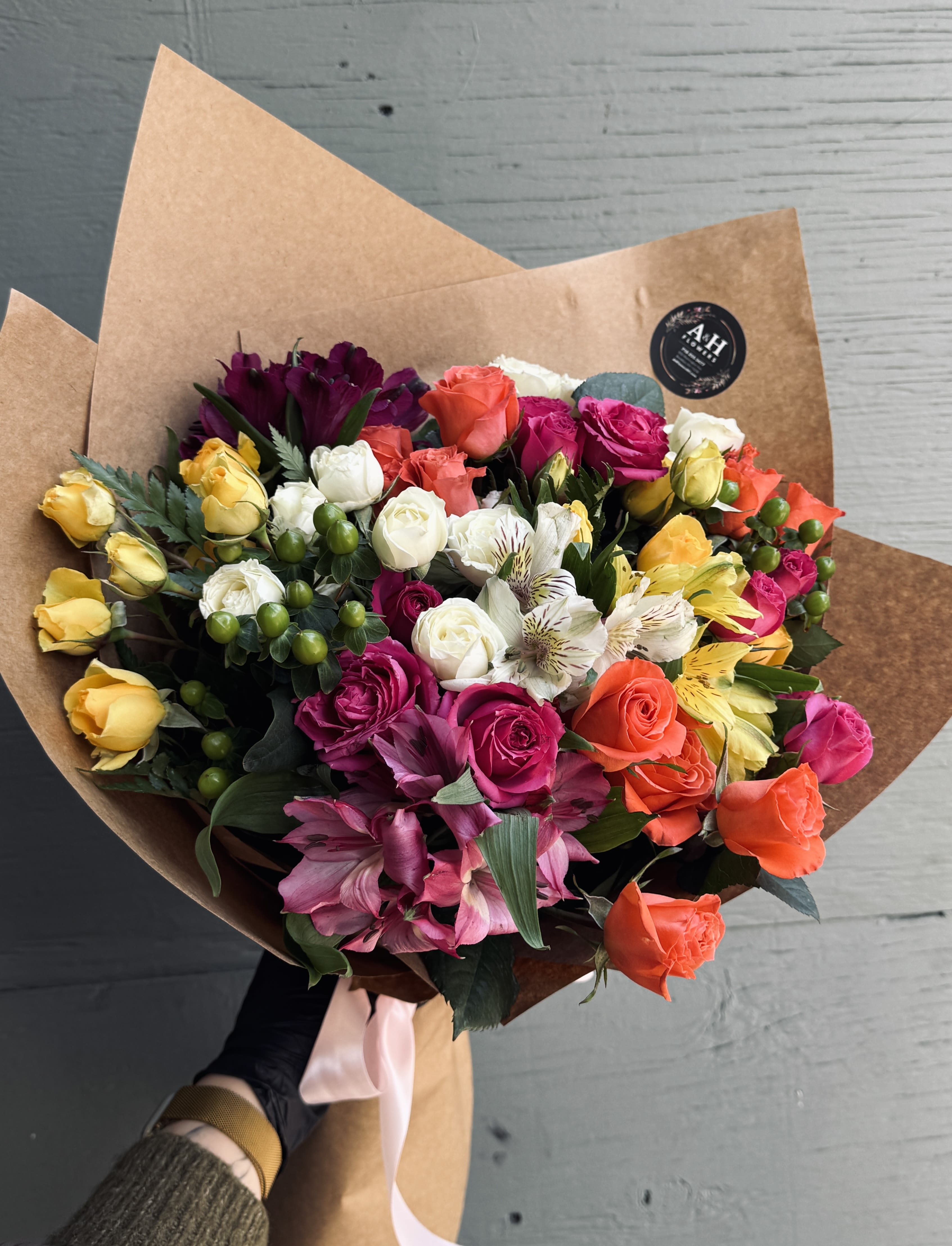 Mixed bouquet of colorful roses and alstroemeria wrapped in brown paper