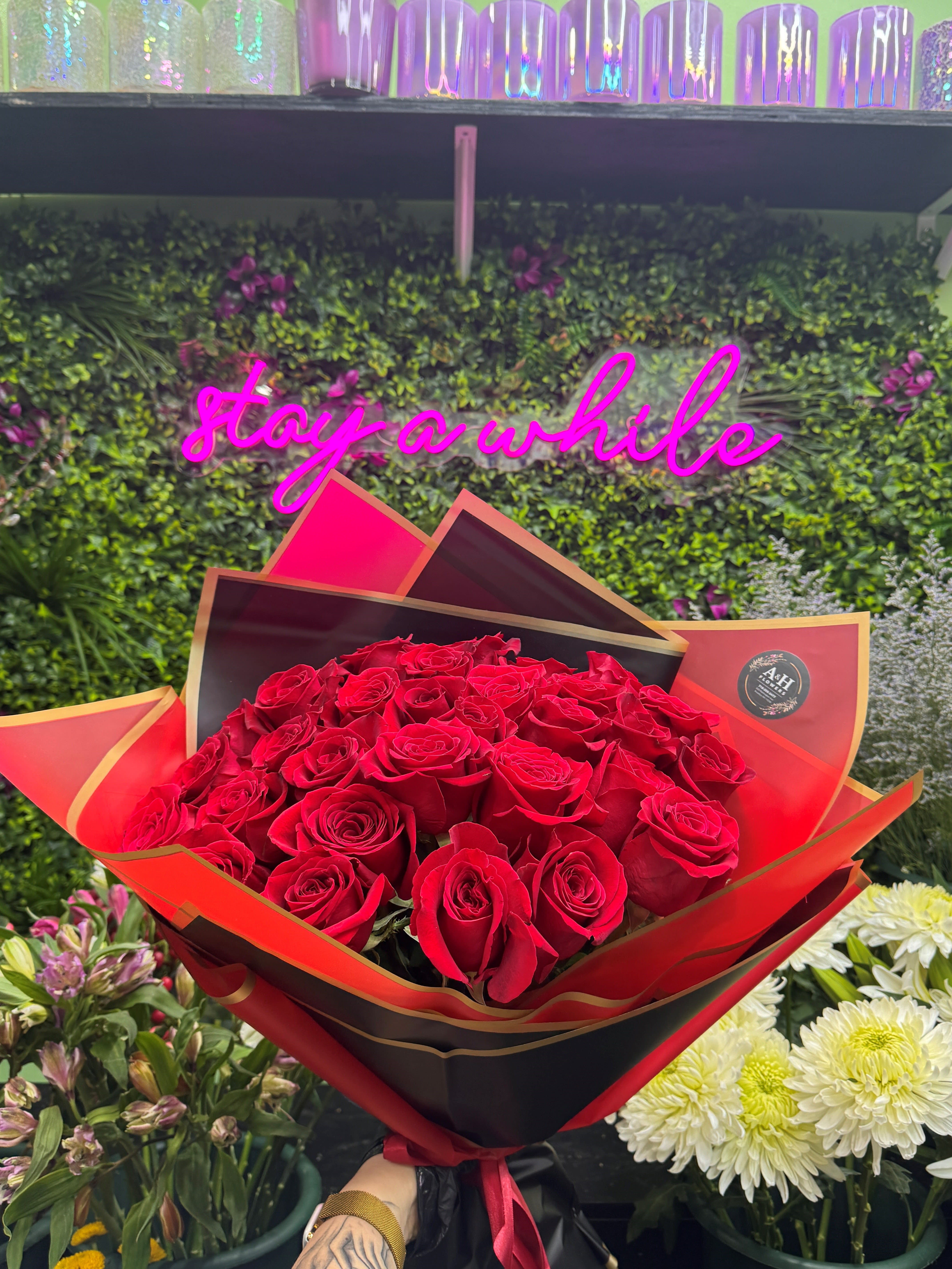 Large bouquet of red roses wrapped in black and red paper held in a flower shop.