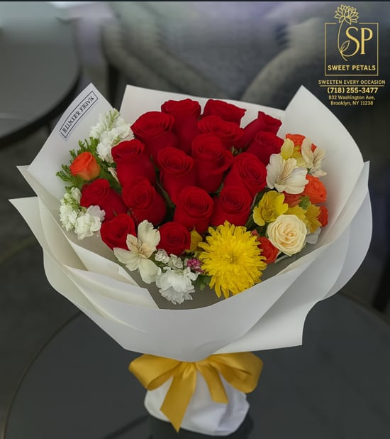 Bouquet of red roses with yellow and white flowers wrapped in white paper