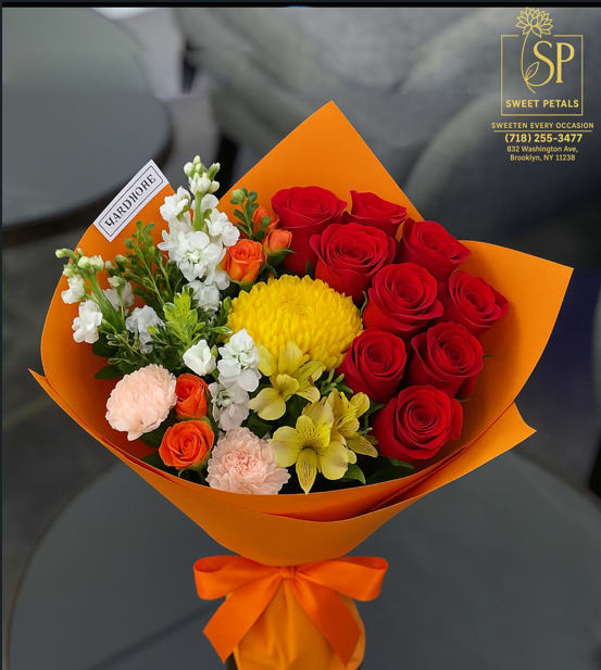 Bouquet of red roses, yellow blooms, and white flowers wrapped in orange paper
