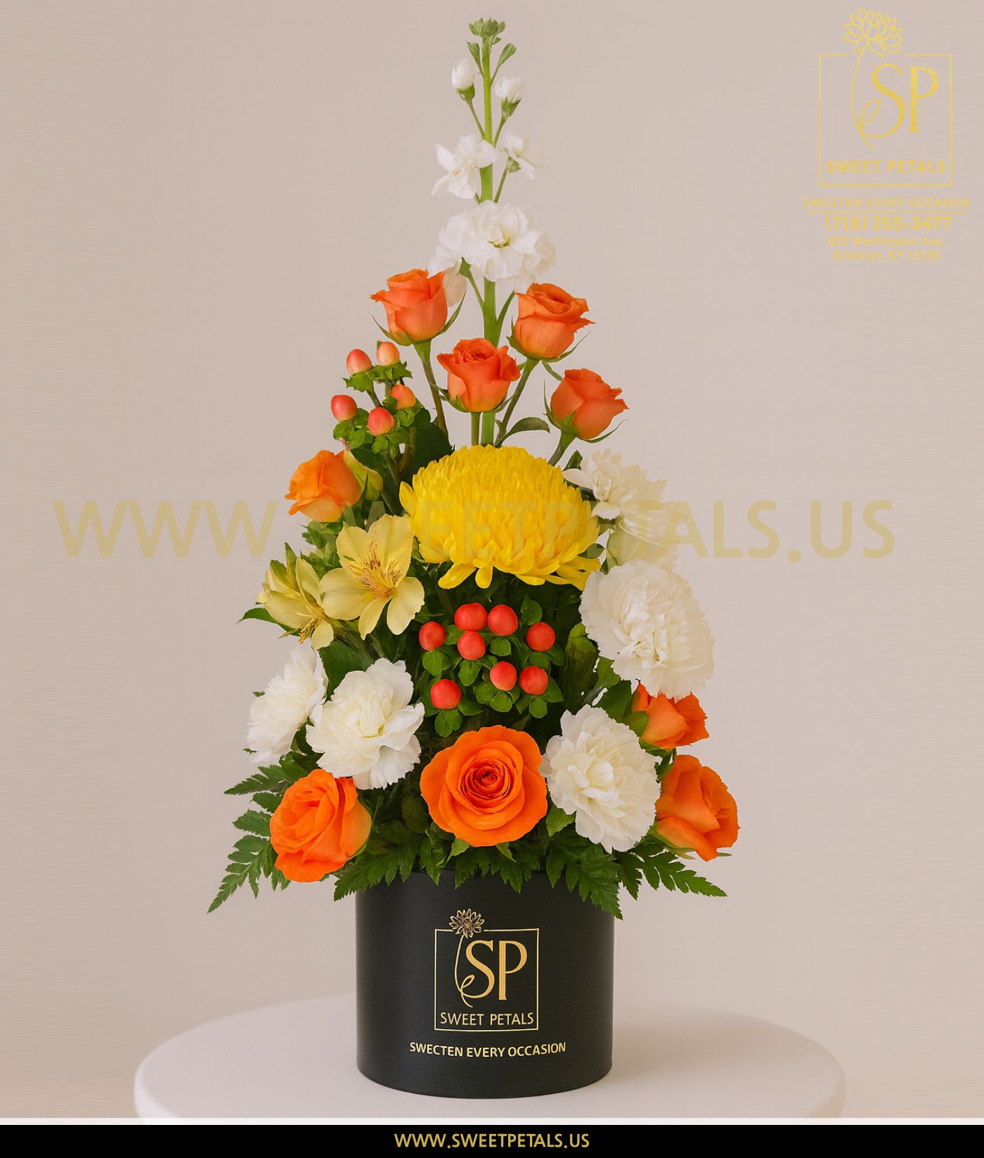 Tall floral arrangement with orange roses, white blooms, and yellow chrysanthemum in a black box