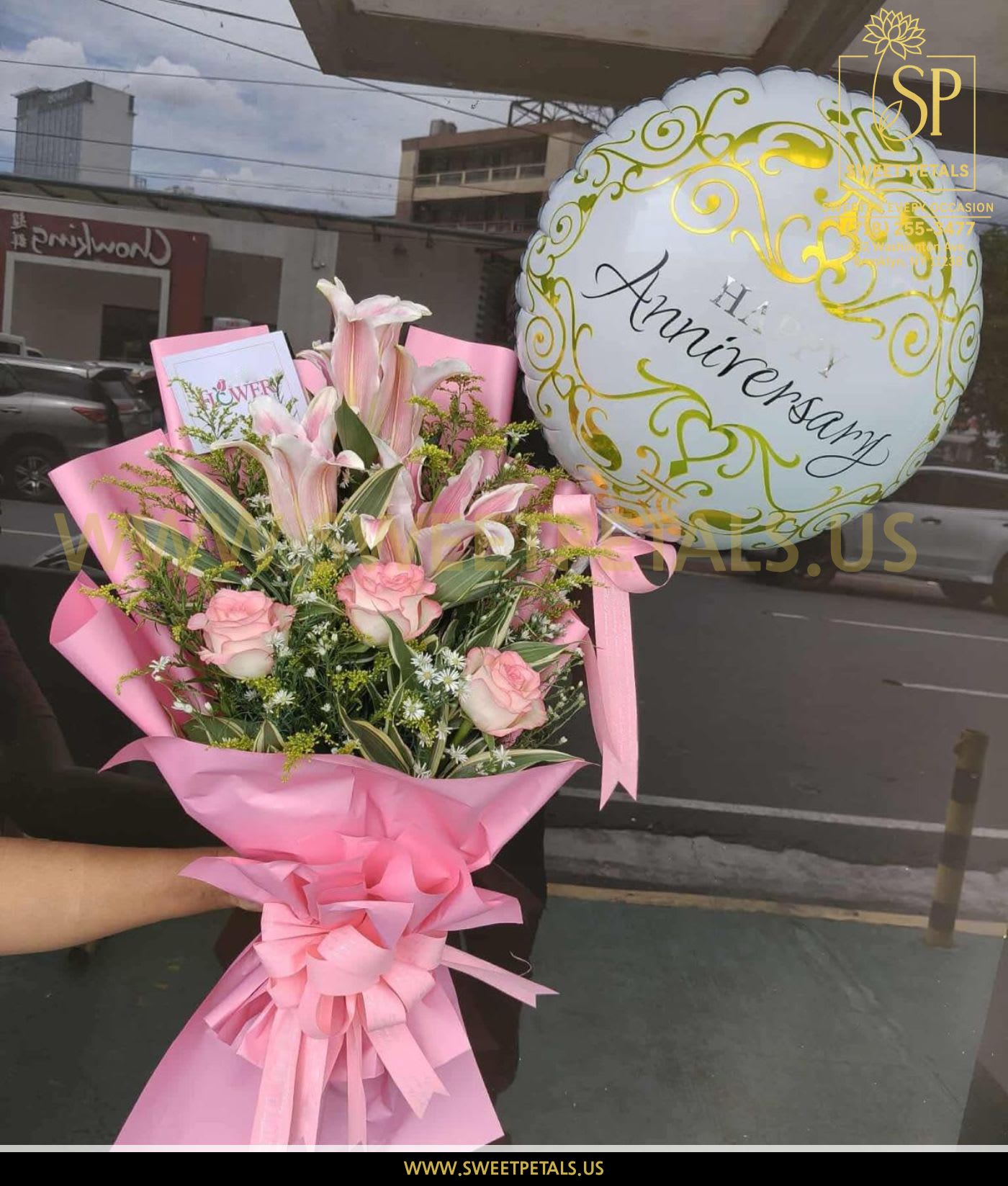 Pink bouquet with roses and lilies beside a white anniversary balloon