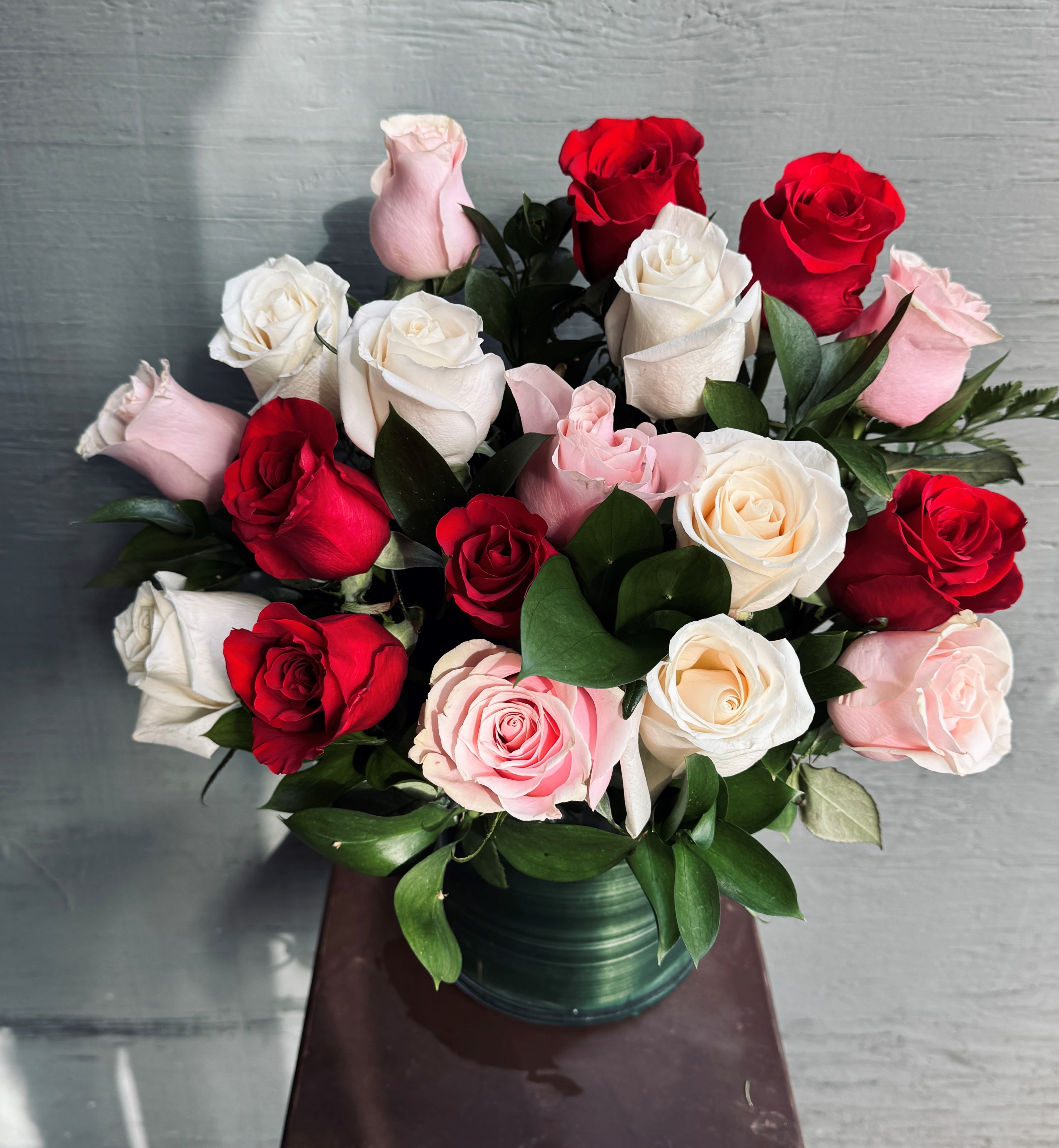 Bouquet of red, white, and pink roses in a green vase