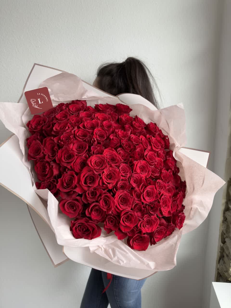 100 Red Roses - Wrapped bouquet - This spectacular bouquet will be perfect for you!  Our hand tied bouquet comes without a vase which makes it perfect for a recipient who loves to arrange flowers on their own or who already has a stellar vase! Bouquet wrapped in pink paper  Perfect for any occasion.