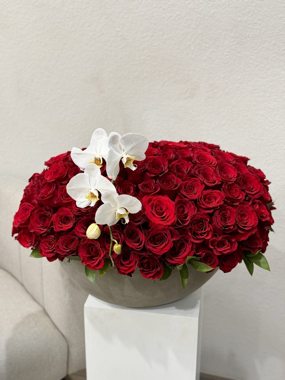 100 Red Roses in a concrete vase - An opulent bouquet of 100 radiant red roses, beautifully arranged in a concrete vase. This Bouquet is a symbol of love and admiration, making a bold and unforgettable statement