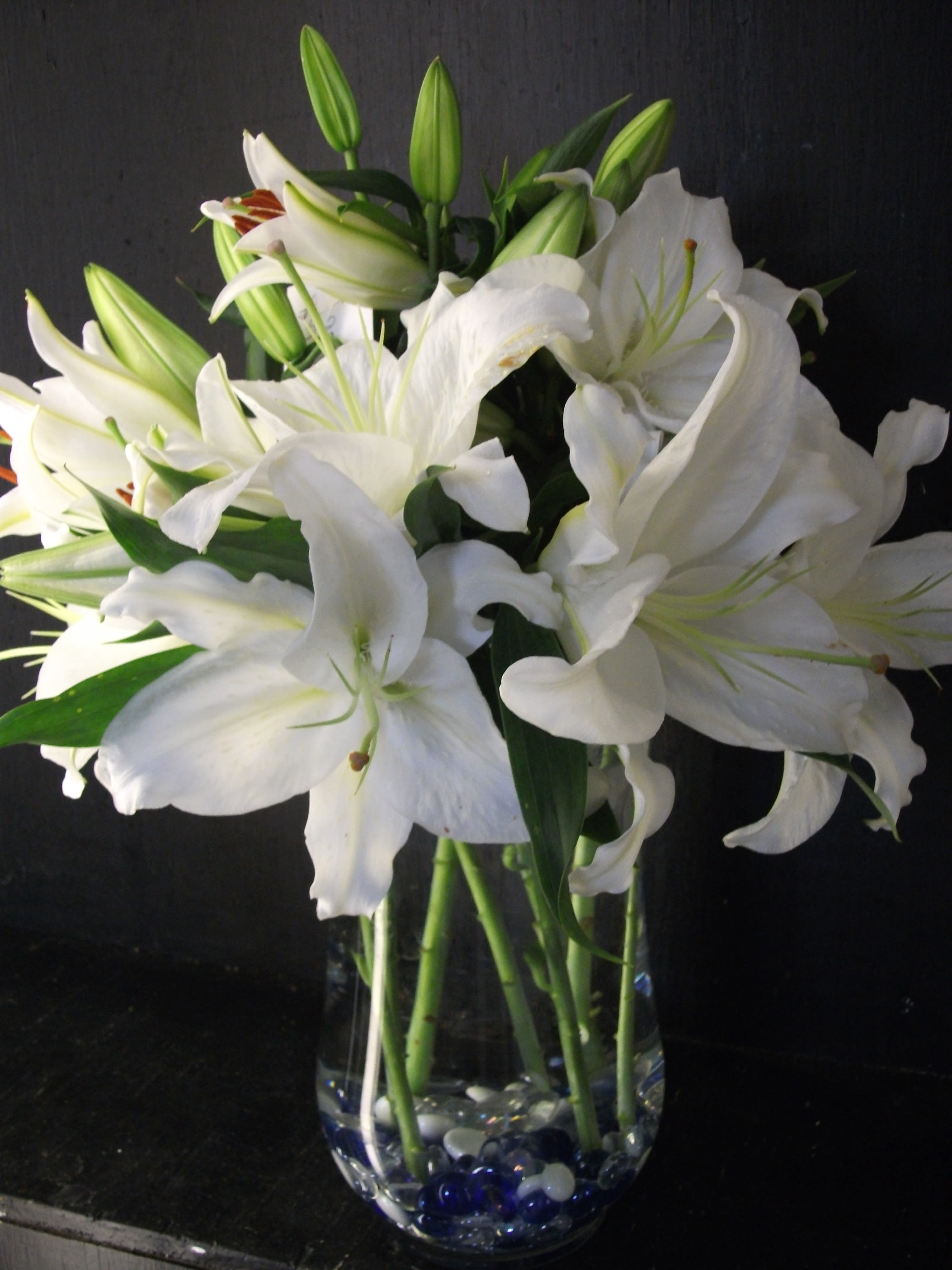 White Reflections White Reflections - White lilies are timeless in a clear vase with colored gems. The White Reflections bouquet is sure to please for all occasions.