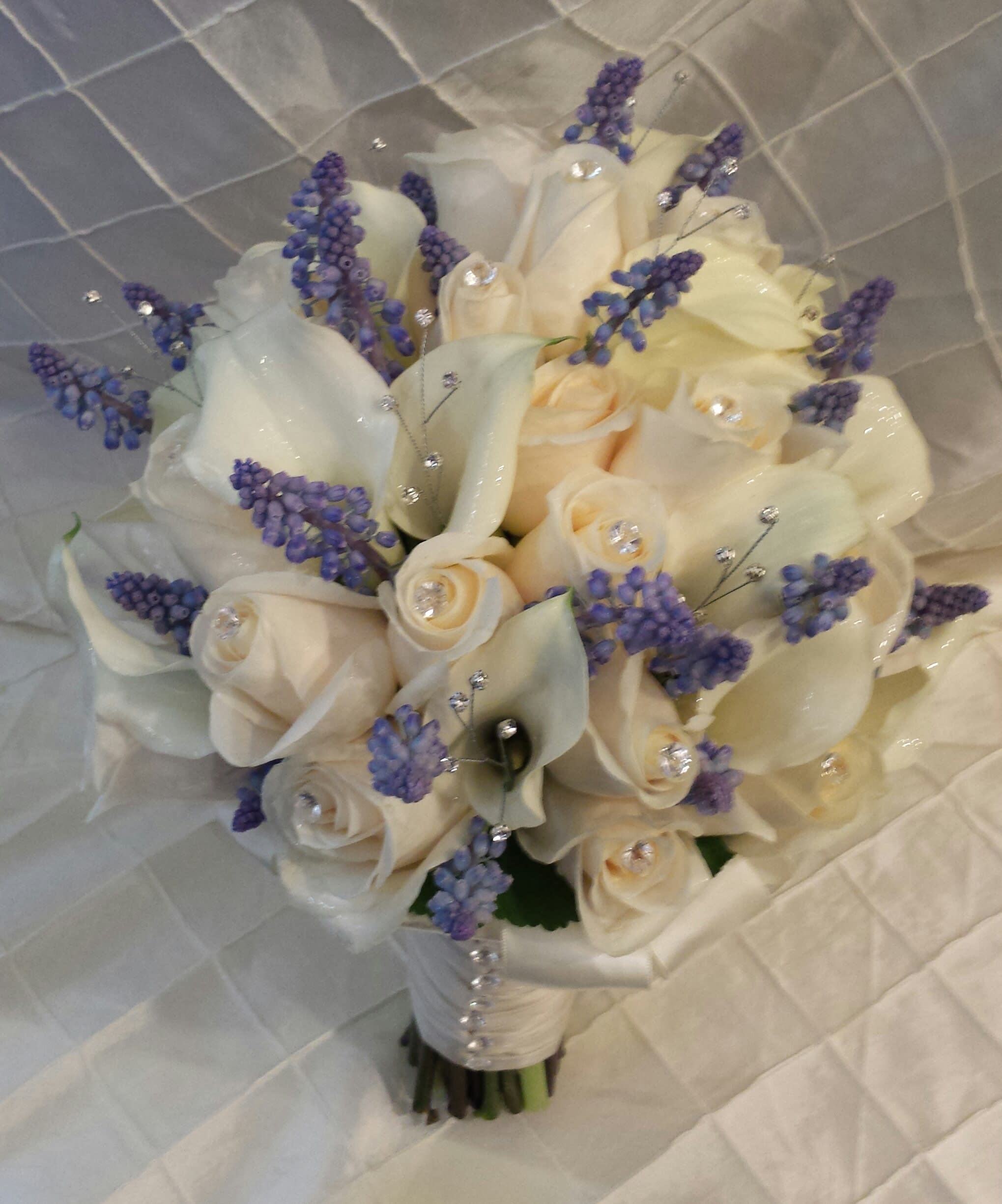 Muscari - A wedding bouquet composed of white roses and white mini calla lilies with beautiful blue muscari accent.