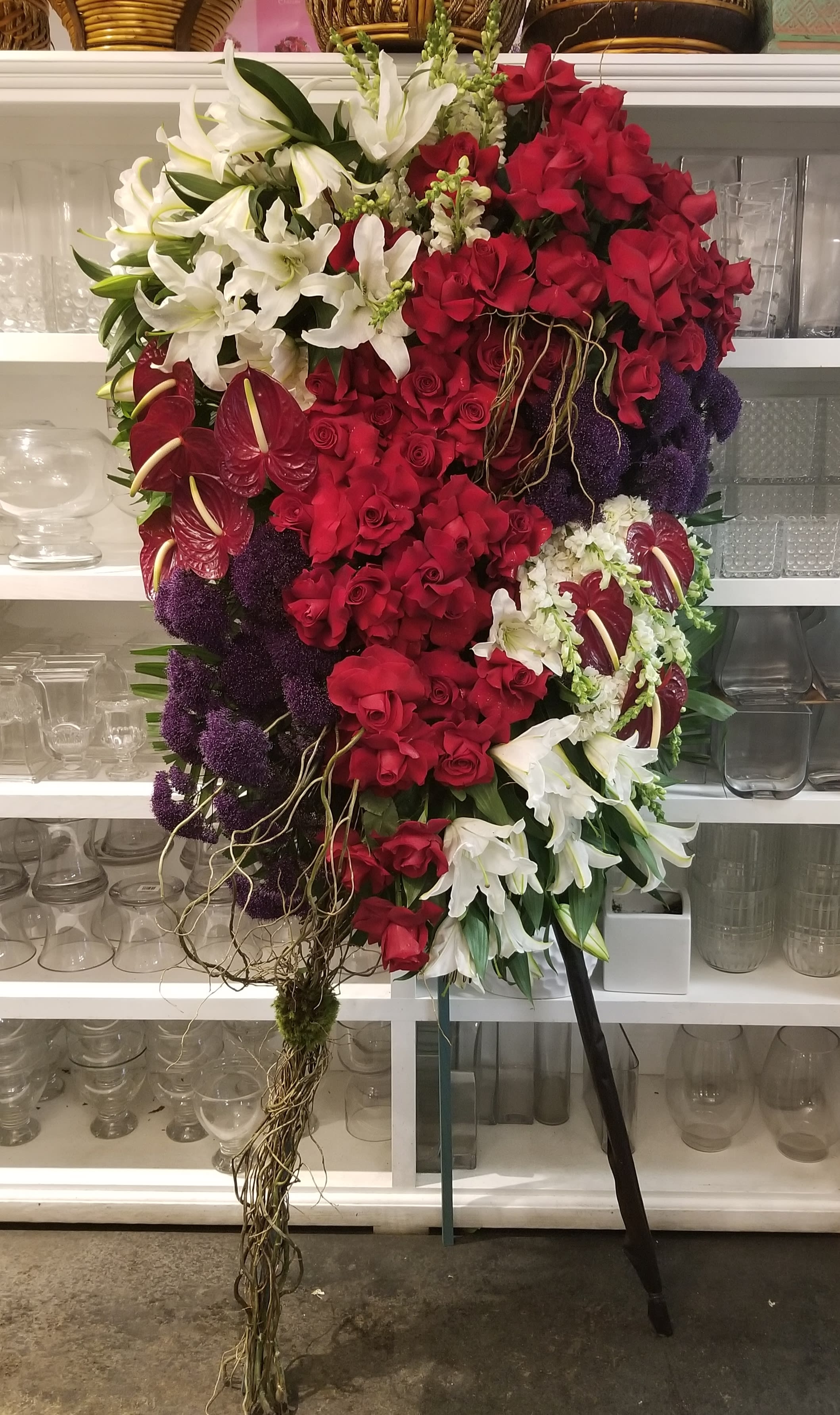 From the Heart - Exotic standing spray of premium flowers in red and white with a touch of purple. It contains lilies, roses, anthurium, purple trachelium and curly willow decor.