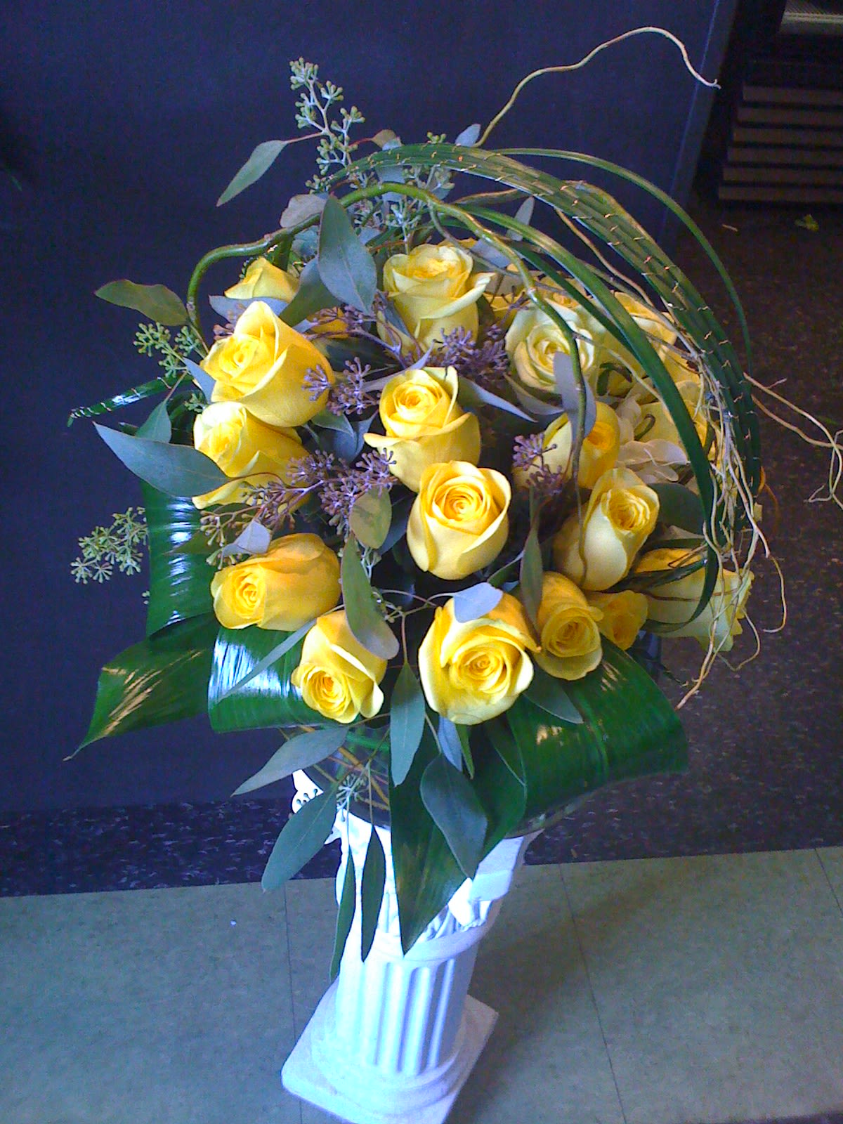 SunShine Delight - 24 Yellow roses vased with grasses and curly willow. Low and Lush, perfect for an office or a coffee table.