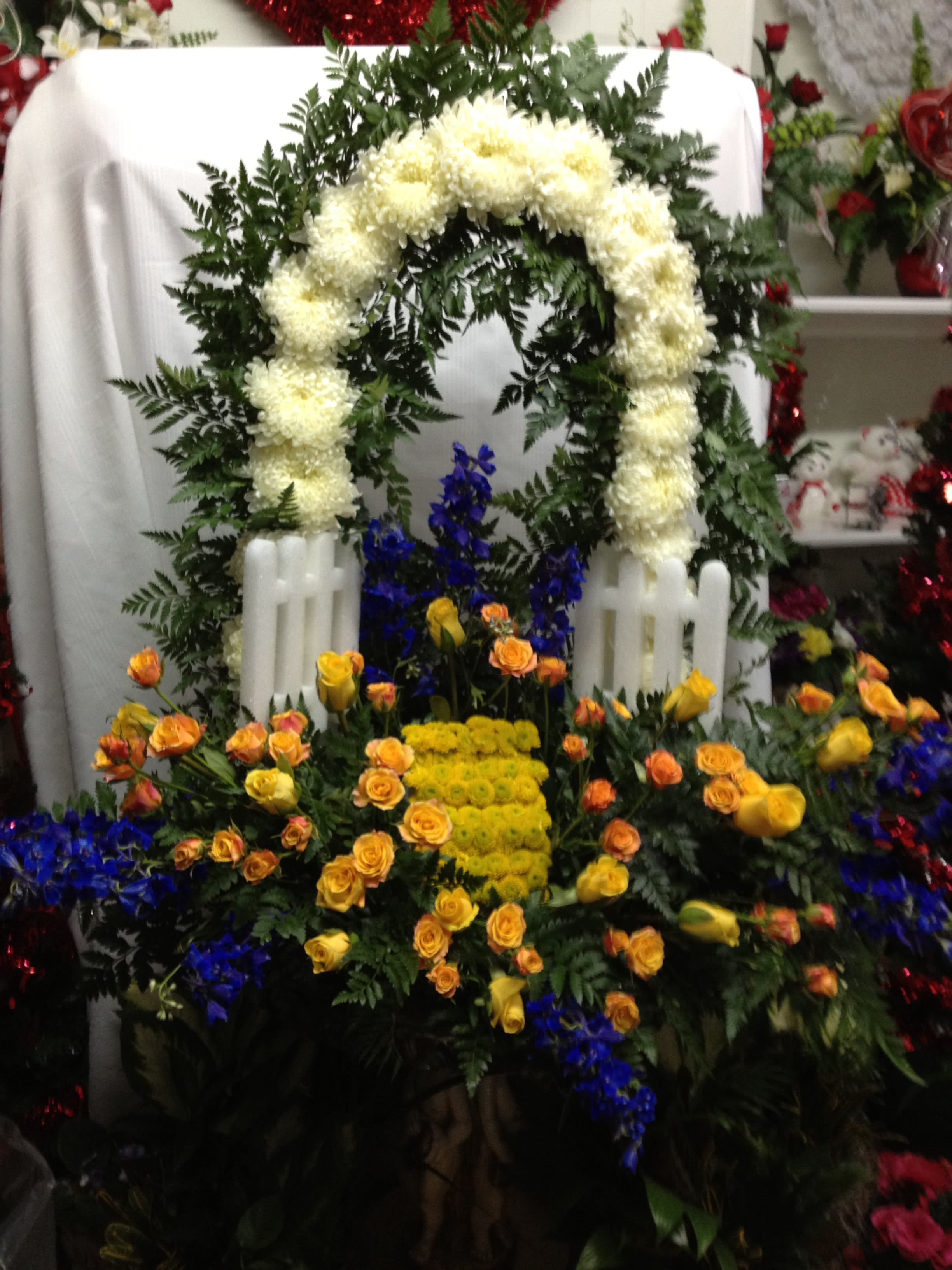 Heaven's Open Gate - * Yellow Roses * Yellow and Orange Spray Roses * Yellow Buttons * White Mums * Blue Delphinium * Leather Leaf This magnificent floral tribute is the perfect way to express your heartfelt sympathy.