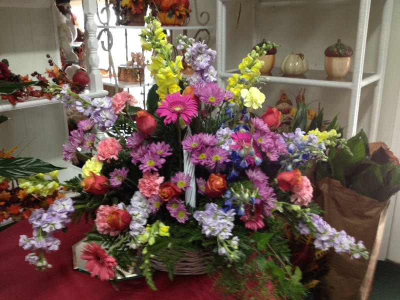 Sympathy Basket - * Yellow Snaps * Lavender Stock * Pink Carnations * Gerber Daisies * Lavender Daisies * Pink Roses * Yellow Carnations * Assorted Greenery including Springeri * White basket This gorgeous bouquet shows those who are bereaved that you really care. Color variations are available.