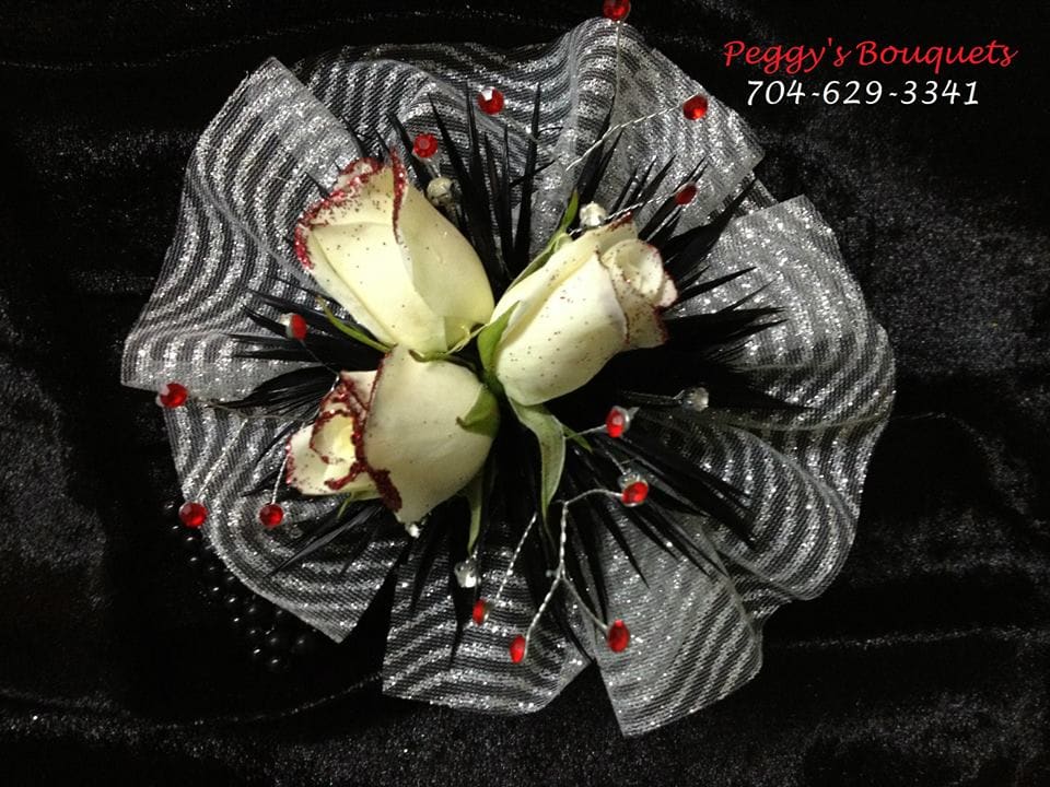 Beautiful corsage with glitter tipped roses, feathers and jewels Beautiful corsage with glitter tipped roses, feathers and jewels - A beautiful corsage with glitter tipped roses, feathers and jewels on black pearl bracelet. Colors vary based on customers design. Diamond or jewel accents also may be added. A jeweled bracelet may also be added.