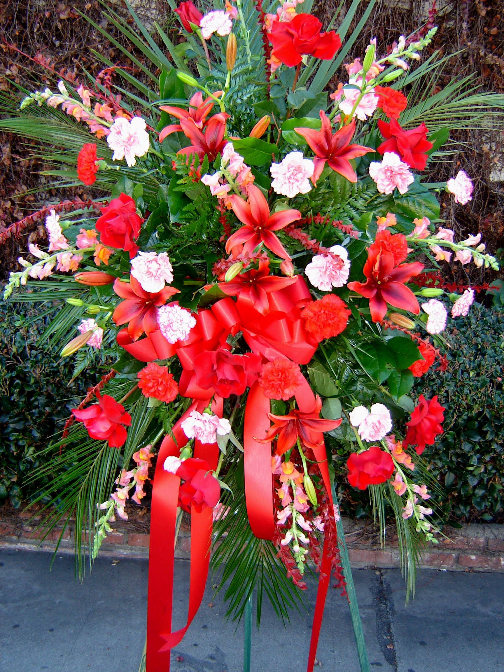 Ruby Red Ruby Red - A funeral easel arrangement that gives quite a punch of red with roses, lilies, carnations, snapdragons and a big bow