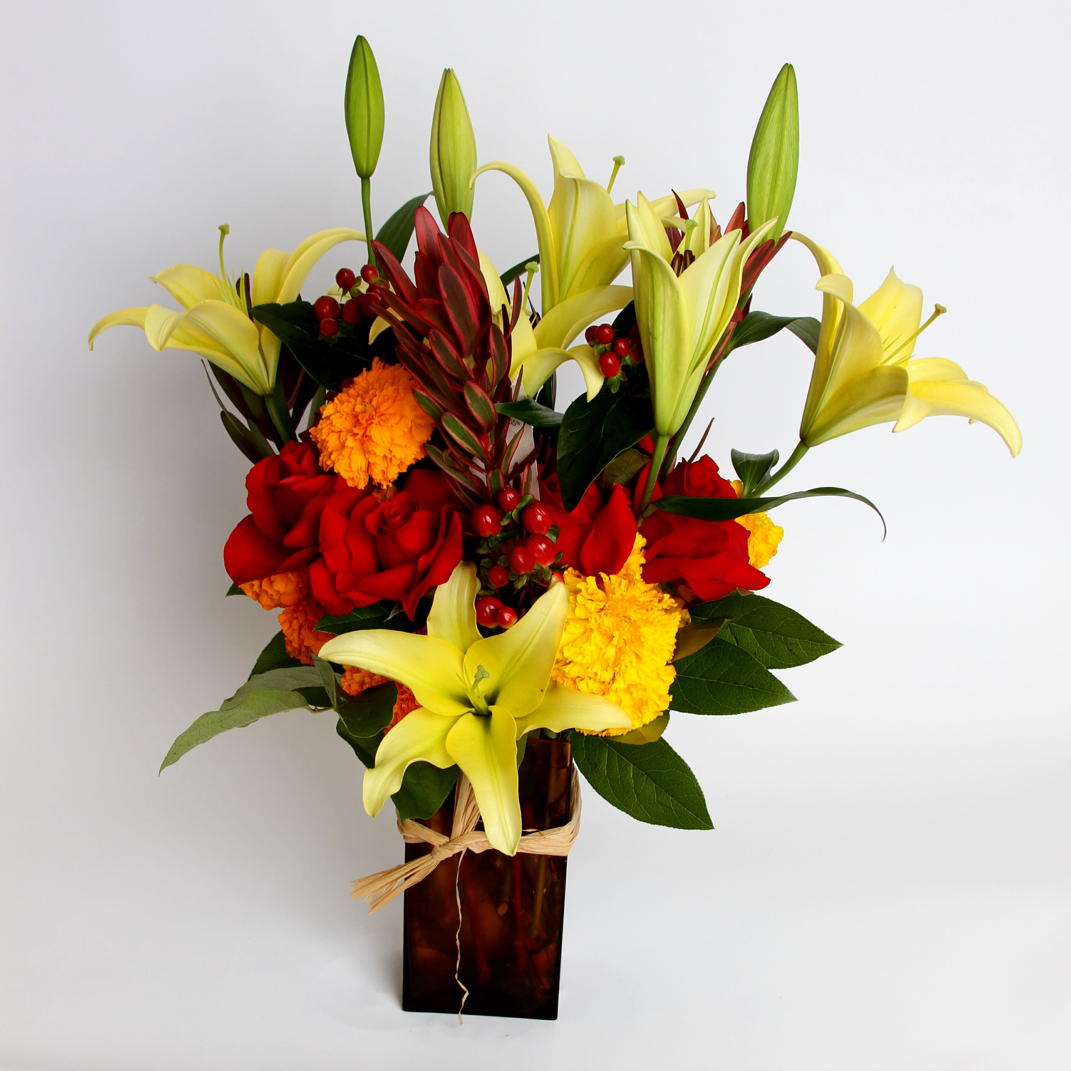 Yellow Lily Yellow Lily - A dynamic vase arrangement with yellow lilies, safari sunset, marigolds, hypericum berries and roses