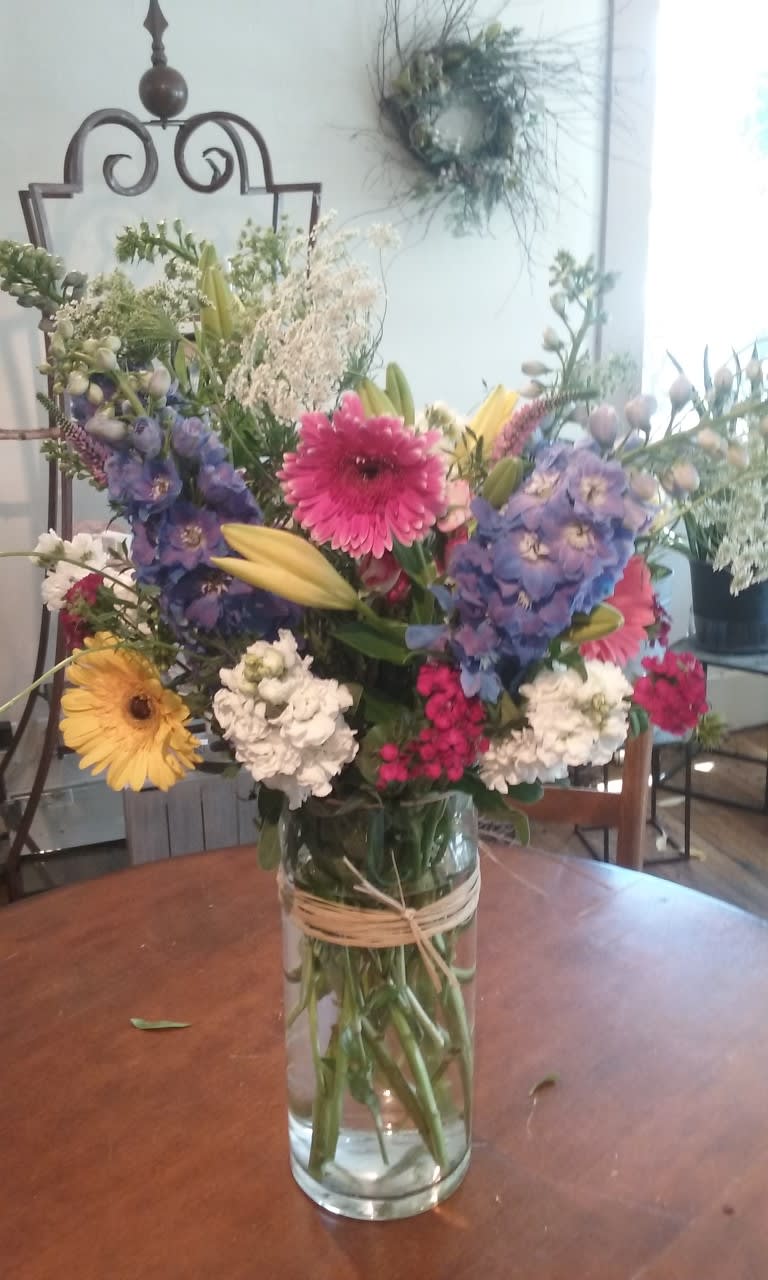 SUMMER CELEBRATION SUMMER CELEBRATION - CLEAR CYLINDER VASE FILLED WITH A SUMMER BOUQUET-WITH A WONDERFUL GARDEN LOOK BASED ON AVAILABILITY DAISIES, DELPHINIUM, QUEEN ANNE LACE, ROSES, LILIES A GARDEN PATH SIGNATURE BOUQUET