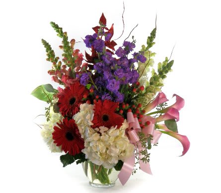 Abundant Love Abundant Love - Let her know the abundance of your love with this elegant arrangement. White hydrangea, red gerber daisies, purple stock, and white and pink snapdragons, accented with fresh greens and curly willow in a clear glass vase finished off with a pink bow. Premium arrangement shown.
