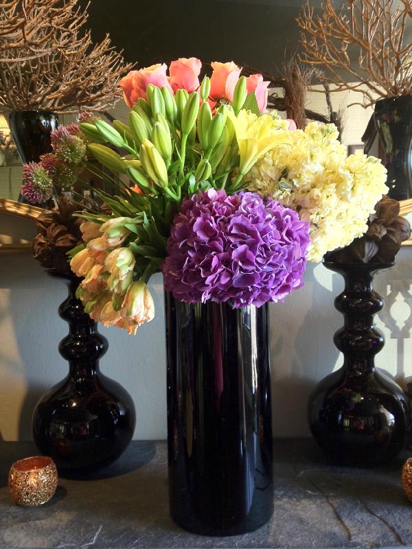 Spring Love - An arrangement of hydrangea, tulips, stock flower, roses, allium and lilies in a tall sleek black vase.