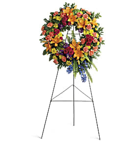 Garden of Love and Serenity Wreath Garden of Love and Serenity Wreath - A rainbow of love. Celebrate your colorful memories of a beautiful life with this radiant wreath of hydrangea, roses and lilies. This wreath features green hydrangea, hot pink spray roses, orange asiatic lilies, orange carnations, blue delphinium, purple stock, yellow cushion spray chrysanthemums, huckleberry, variegated pittosporum, sword fern, silver dollar eucalyptus, and lemon leaf. Delivered on a wire easel. Approximately 27 3/4" W x 34" H Floral Availability may vary based upon seasonality. In these instances, same color composure will be maintained.