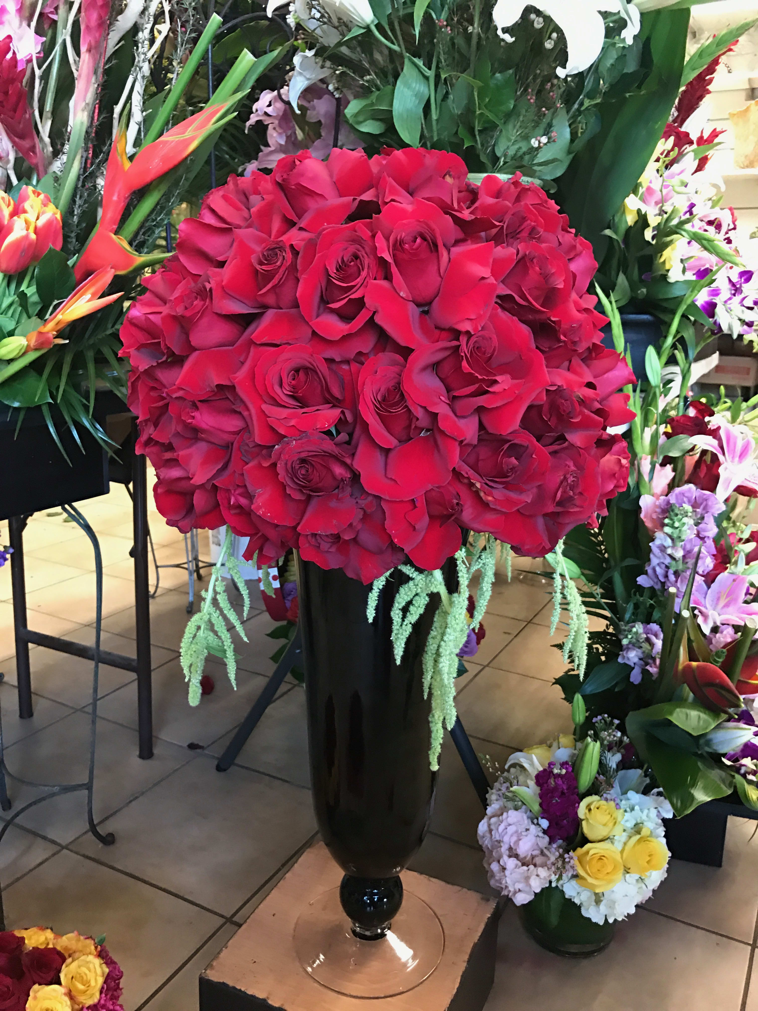 Centerpiece on top of a beautiful vase - This beautiful red centerpiece will surely catch the eye of everyone as it sits on top of a beautiful tall black vase. The gift that will make catch everyone's attention.