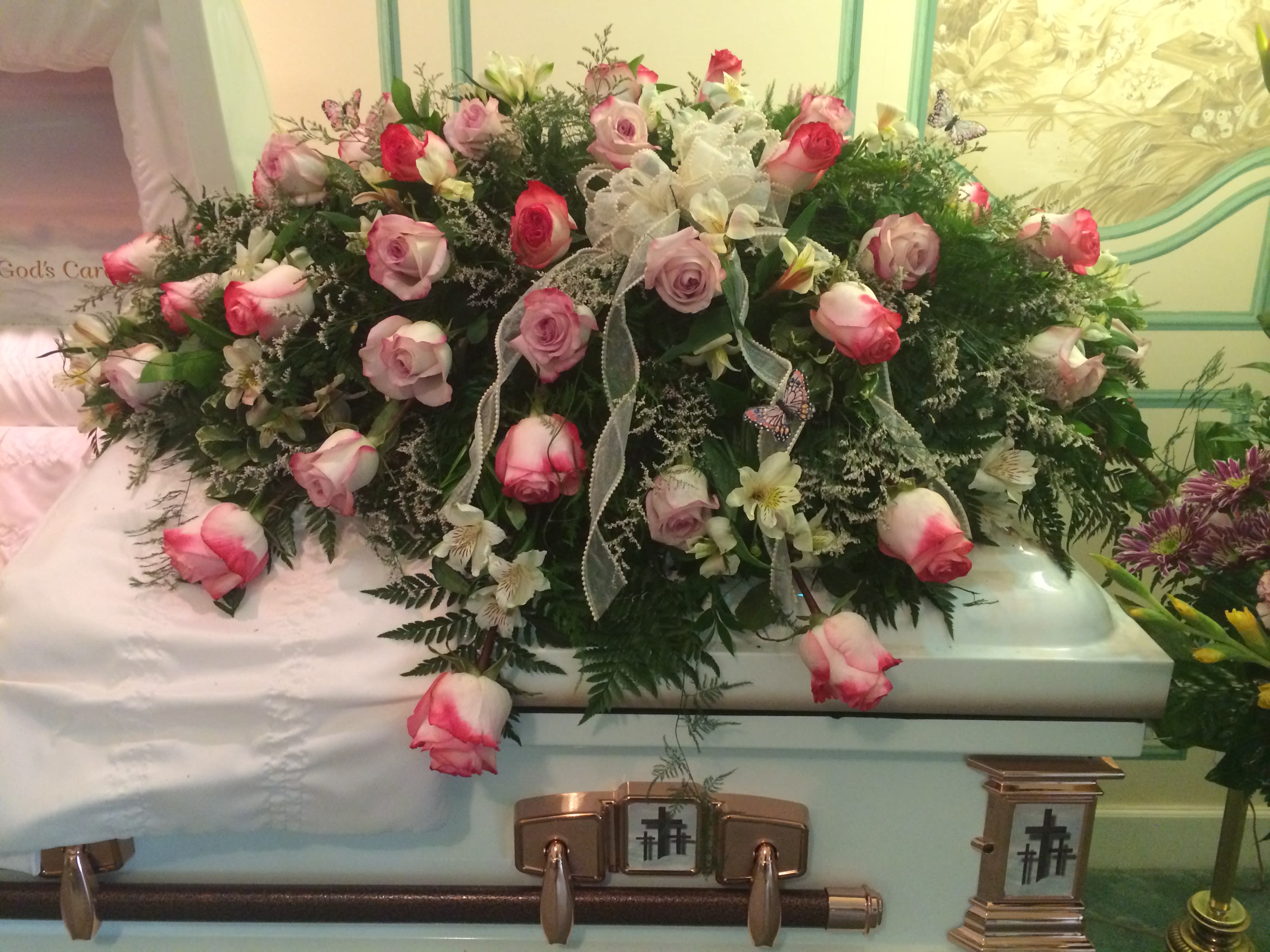 Pink Tipped Roses and Butterflys Pink Tipped Roses and Butterflys - Casket Spray of pink tipped roses with a pearl lined bow and accented with feather butterflys