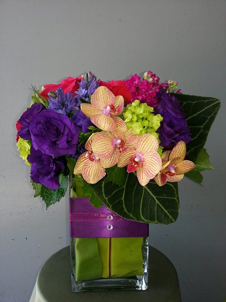 Isobel - Lisianthus, Assortment of Orchids, Hyacinth, Hydrangea, Roses, Exotic Leaves, with wrapped vase.