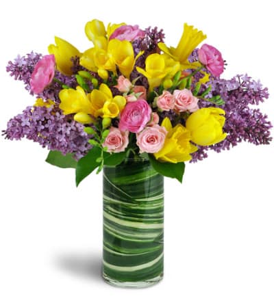 SPRING SMILES - Lilacs, tulips, and more - oh my! This cheerful arrangement will bring smiles and the delight of Spring to a special friend or coworker, and it's perfect for Mother's Day, too! 