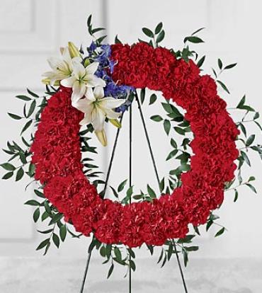 To Honor One's Country Wreath To Honor One's Country Wreath - A patriotic expression of respect and sympathy. This arrangement of red carnations is accented with white lilies and blue delphinium, with greens. Delivered on an easel and appropriate to send to a funeral home or service. Item # S28-3548