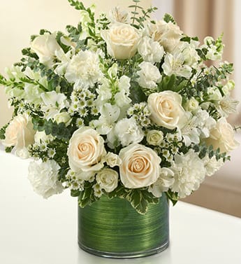 Cherished Memories - All White - Product ID: 95379   Send a gift of lasting tribute and touching remembrance of a life well lived. This striking, all-white arrangement of roses, spray roses, snapdragons, alstroemeria, carnations and more, elegantly arranged by hand in a graceful cylinder vase. A lovely gift of comfort and honor. Fresh arrangement of white roses, spray roses, snapdragons, alstroemeria, carnations, mini carnations, and monte casino, gathered with variegated pittosporum and spiral eucalyptus Hand-designed by our expert florists in a stylish clear glass cylinder vase wrapped with a Ti leaf ribbon; vase measures 6&quot;H Appropriate for the service or for sending to the home of friends and family members Large arrangement measures approximately 16&quot;H x 17&quot;L Medium arrangement measures approximately 15&quot;H x 16&quot;L Small arrangement measures approximately 14&quot;H X 15&quot;L Our florists hand-design each arrangement, so colors, varieties, and vase may vary due to local availability
