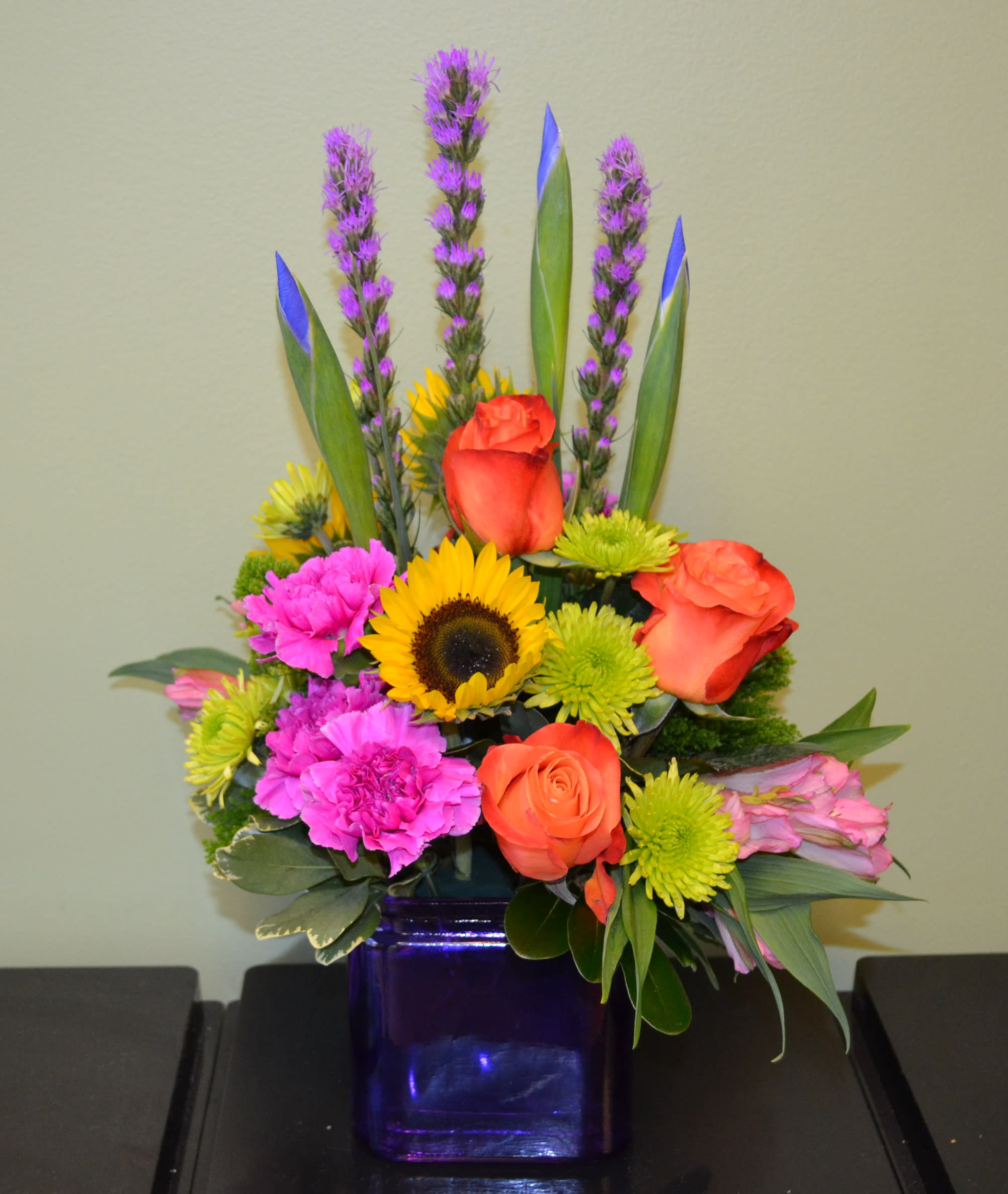 Spring Awakening - Beautiful arrangement including Iris, Liatris, Sunflowers, Orange roses, Magenta Carnations and more!