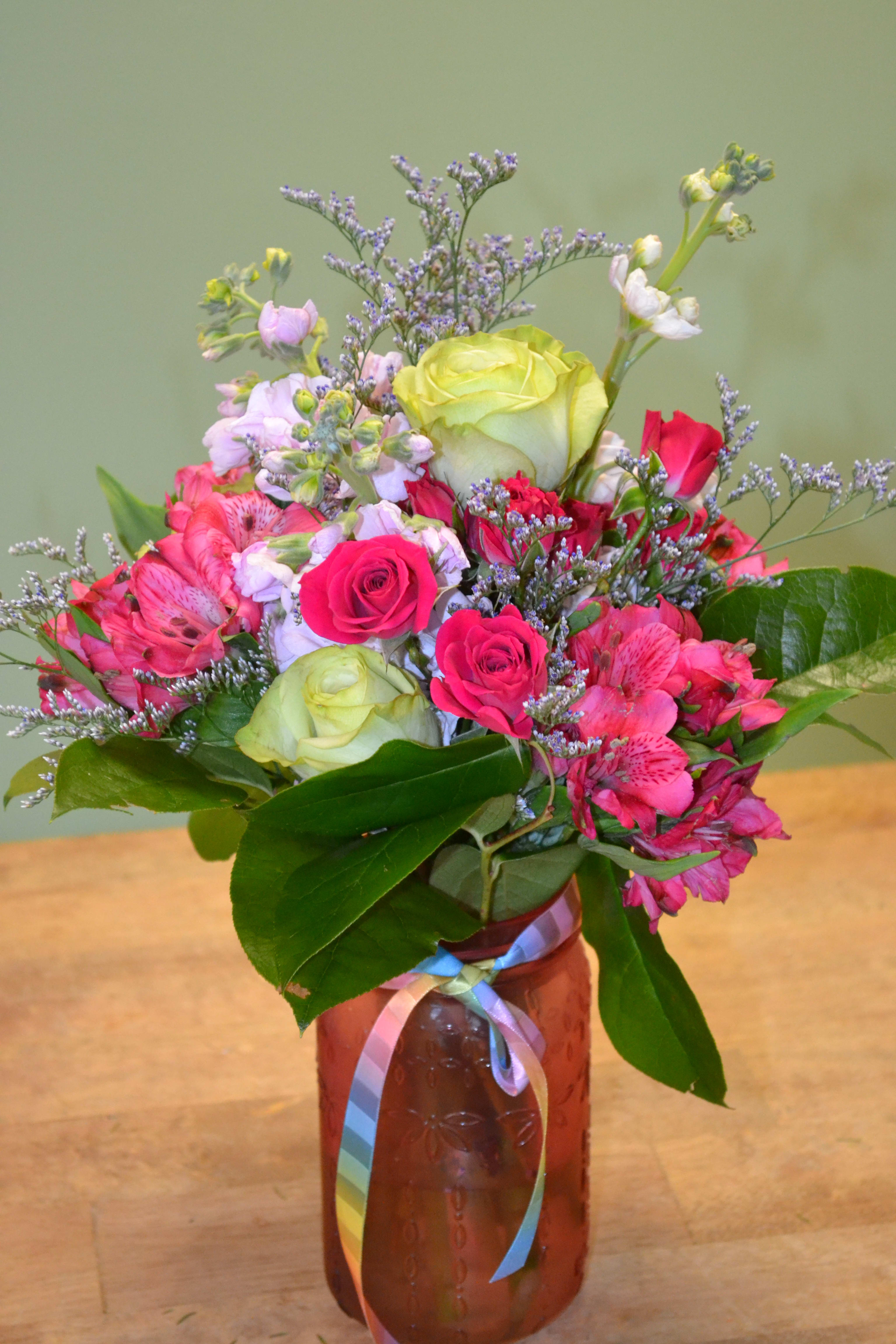 Springtime Embrace - A colorful mason jar meets cheerful flowers such as Alstro, Stock, Spray roses, Roses, Limonium and more for a refreshing touch.