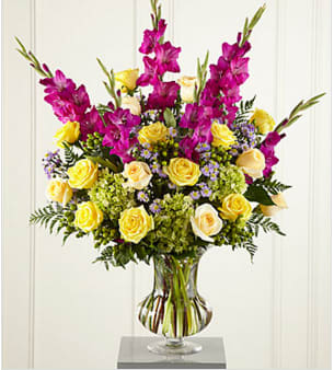The FTD® Loveliness™ Arrangement The FTD® Loveliness™ Arrangement - Big, colorful, sophisticated. This generously-scaled arrangement makes a fresh and loving tribute to a life lived in beauty and grace. A superb choice for a wake or a funeral service, this colorful bouquet is handcrafted by a local FTD artisan florist of yellow and cream roses, fuchsia gladiolus, lavender monte casino, green hypericum berries and hydrangea with accents of greenery in a premium glass vase. You can count on its making a comforting impression that will be long-remembered. Your purchase includes a complimentary personalized gift message.